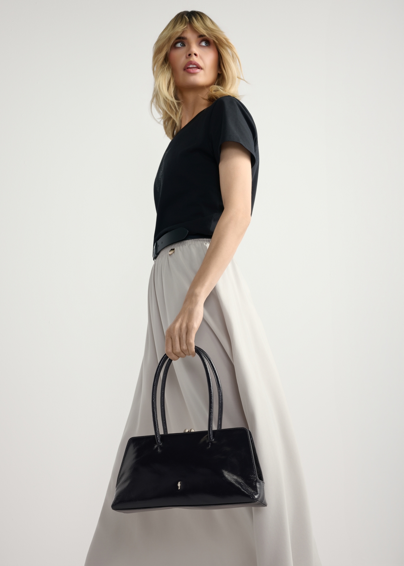 Dark navy blue small leather women's handbag TORES-1293-7EW26), view of the product in the model's hand, on a light background.