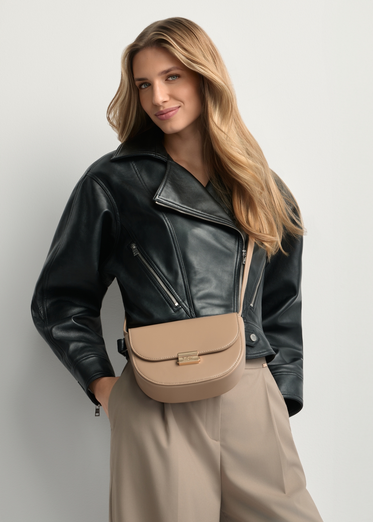 Beige semi-circular women's messenger bag TOREC-1127-1D(W26) - front view of the product, on a model, against a light background. Half of the silhouette visible.