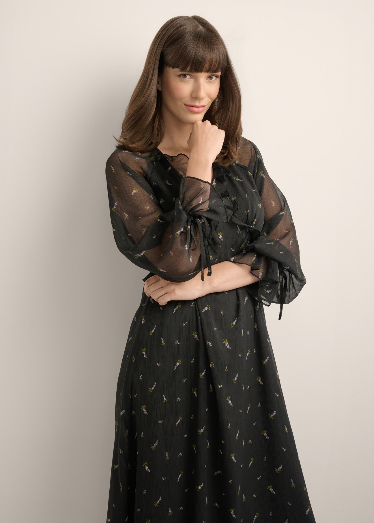Black maxi dress with a lilac pattern and ruffles SUKDT-0290-9P(Z26), product view from the front on the model. Half of the silhouette visible.