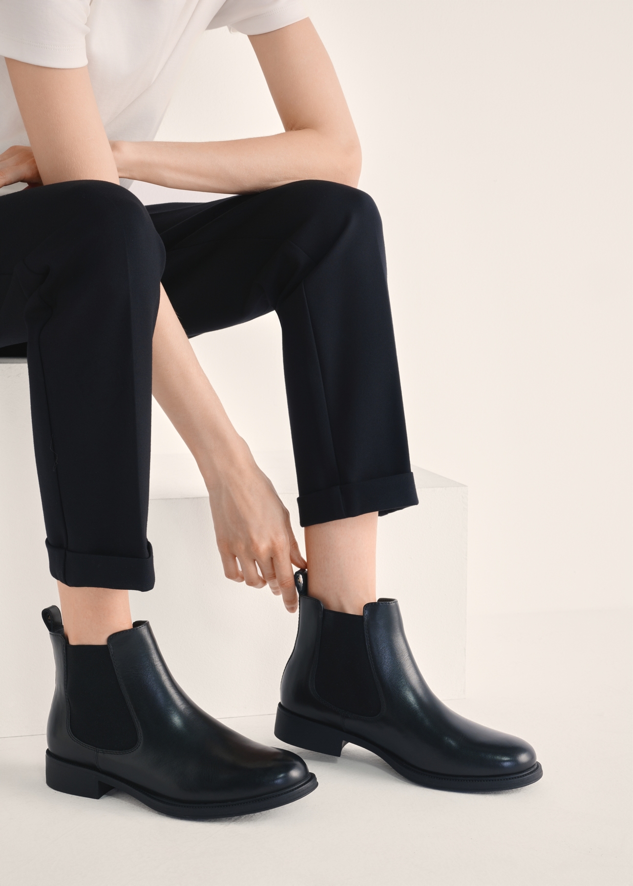 Women's black leather short Chelsea boots BUTYD-1116-99(Z25), product view on the model's feet against a light background.