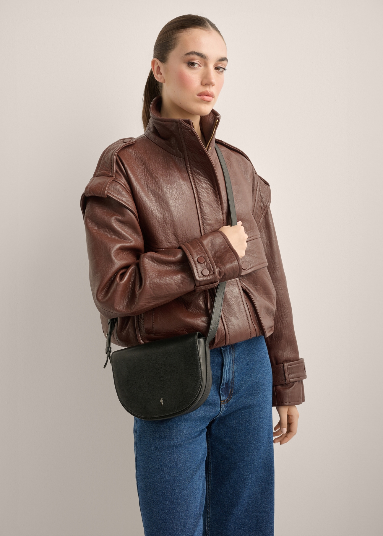 Women's black leather messenger bag TORES-1352-99(Z26), diagonal view of the product on the model. Half of the silhouette visible.