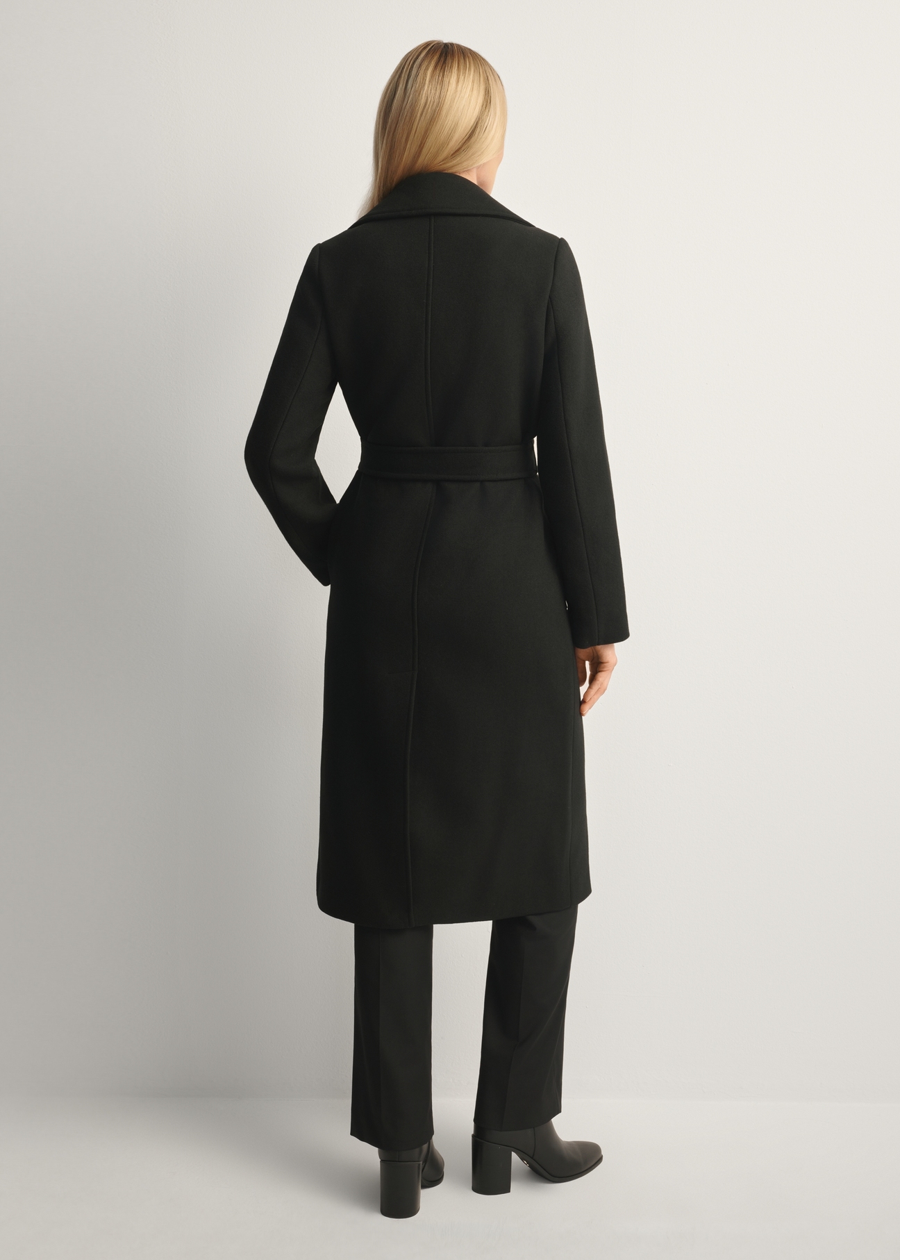 Black long women's coat PLADT-0048B-99(Z25), product view from the back on the model, the whole silhouette is visible.