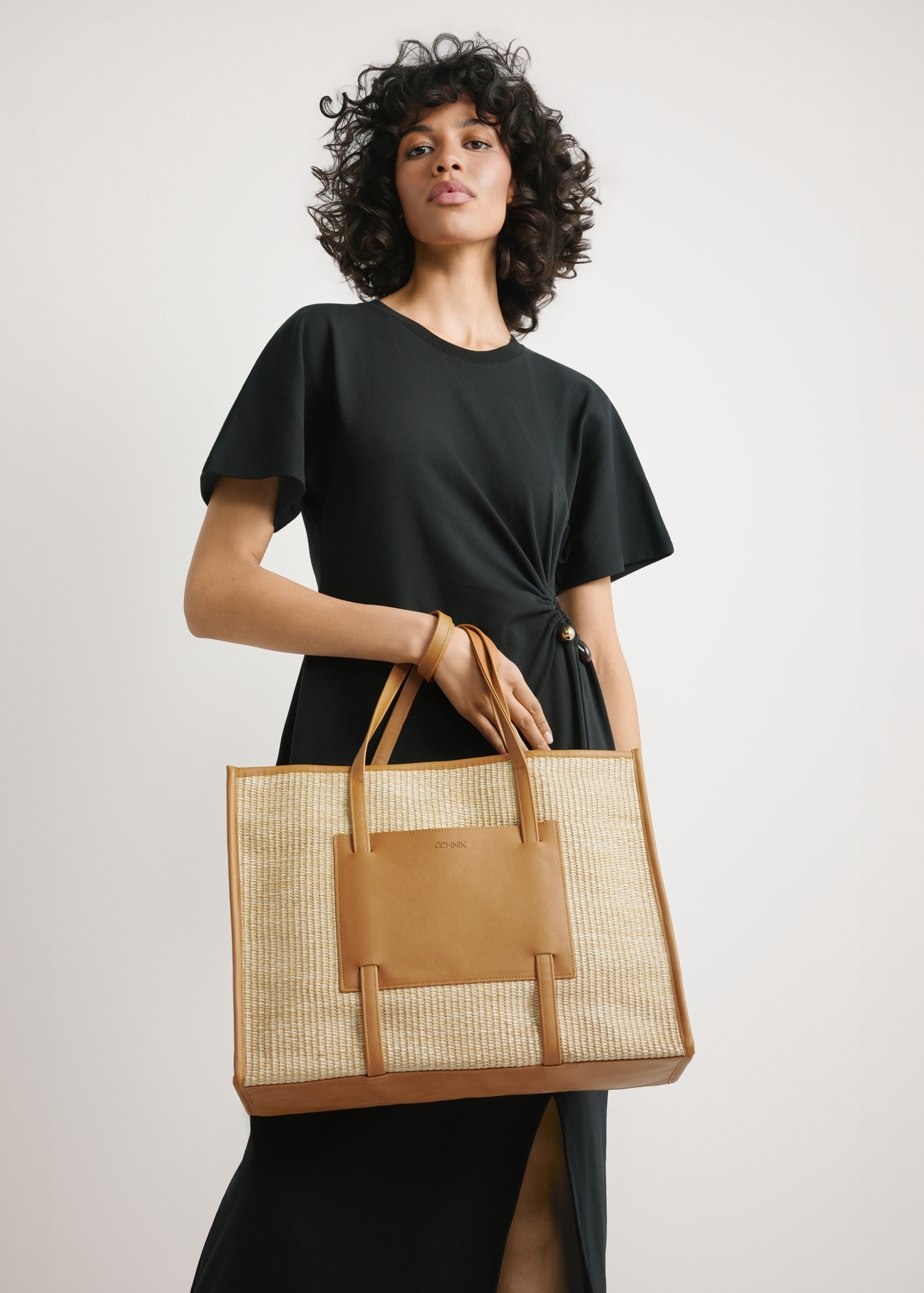 Large women's straw handbag TOREC-1224-1E(W26) - view of the product held in the model's hand, against a light background. Half of the silhouette is visible.