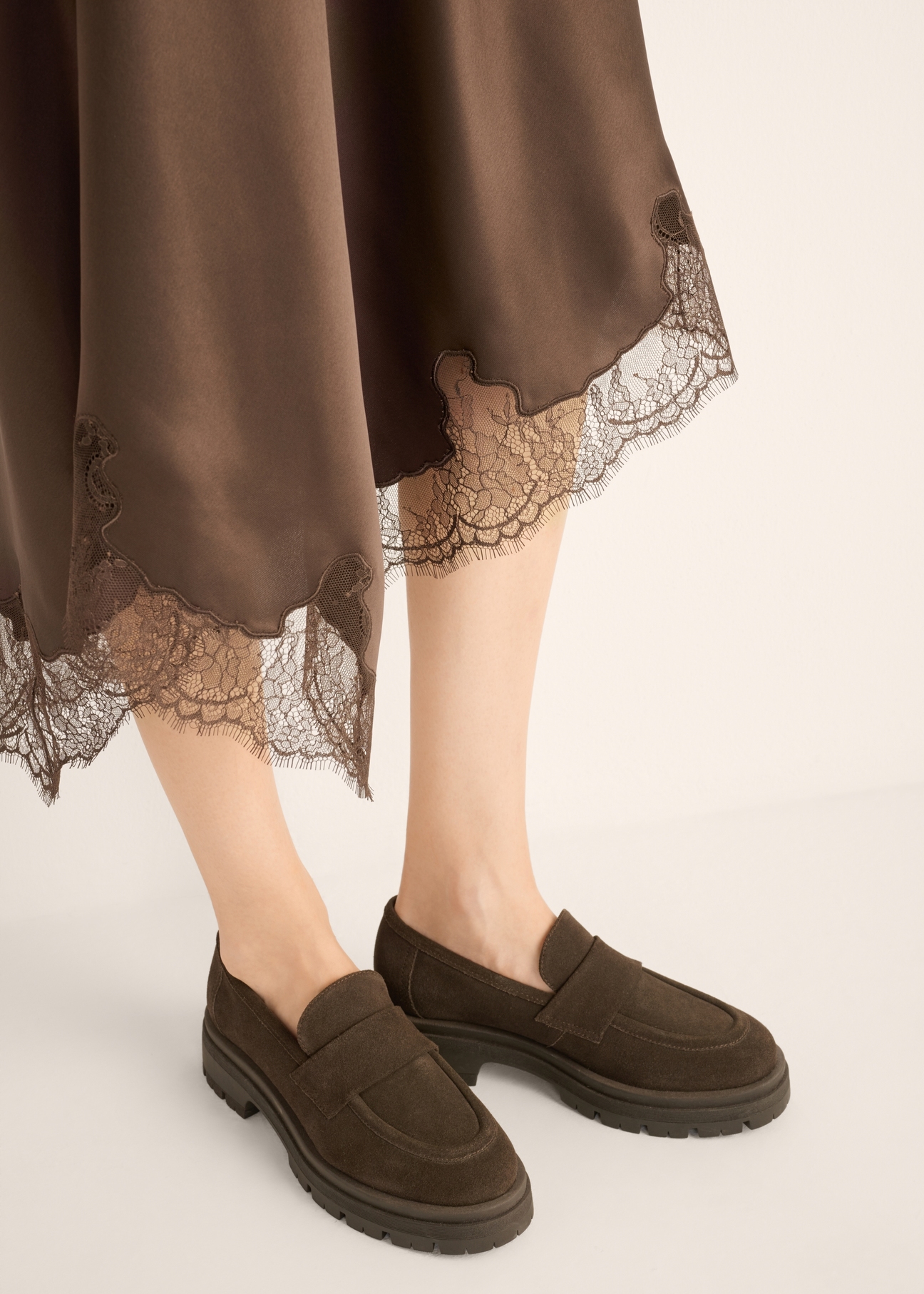 Women's dark brown suede moccasins BUTYD-1187-1I(Z26), diagonal view of the product on the model. Half of the silhouette visible.