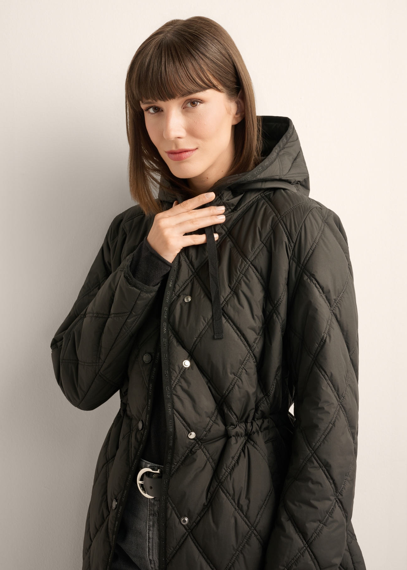 Women's black quilted jacket KURDT-0579-99(Z25), front view of the product on the model. Half of the silhouette visible.