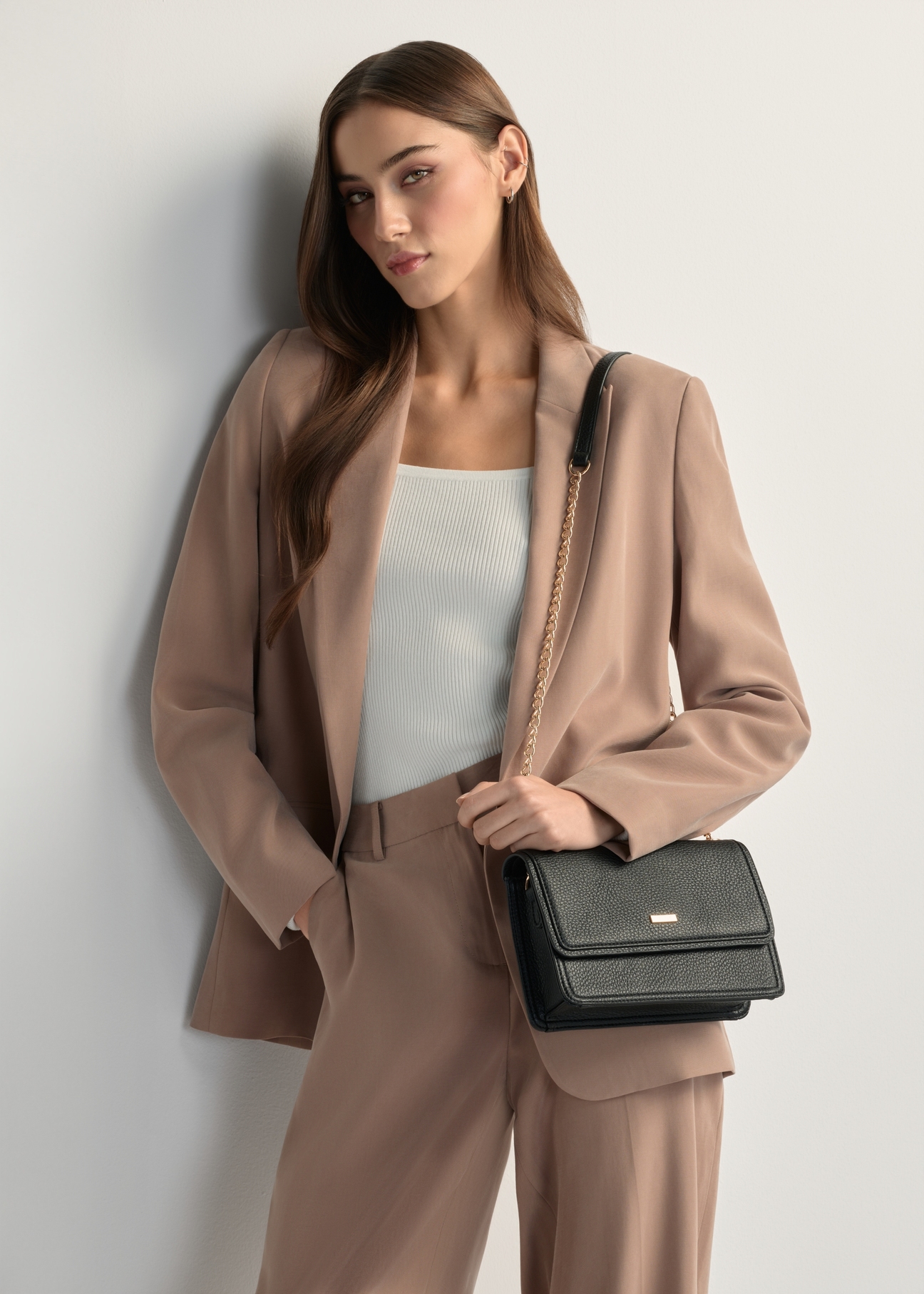 Small, elegant women's handbag TOREC-1015-99(W26), front view of the product on a model, half of the silhouette visible.