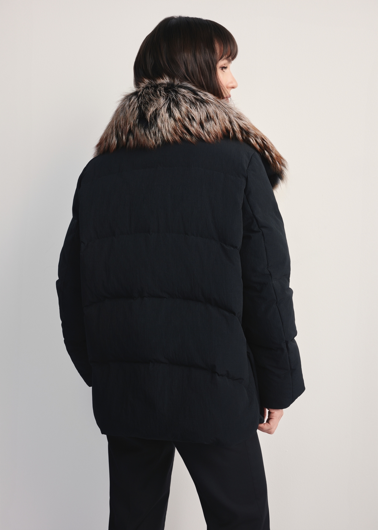 Women's black winter jacket with natural fur KURDT-0592-99(Z25) - back view of the product on a white background. Half of the silhouette visible.