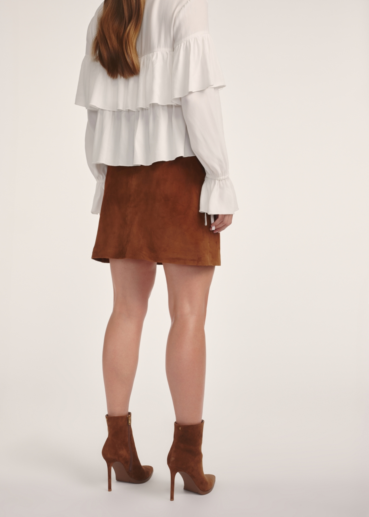 Suede mini skirt in cognac color SPCDS-0078-3205(Z25), product visible from the back on the model, half of the silhouette visible.
