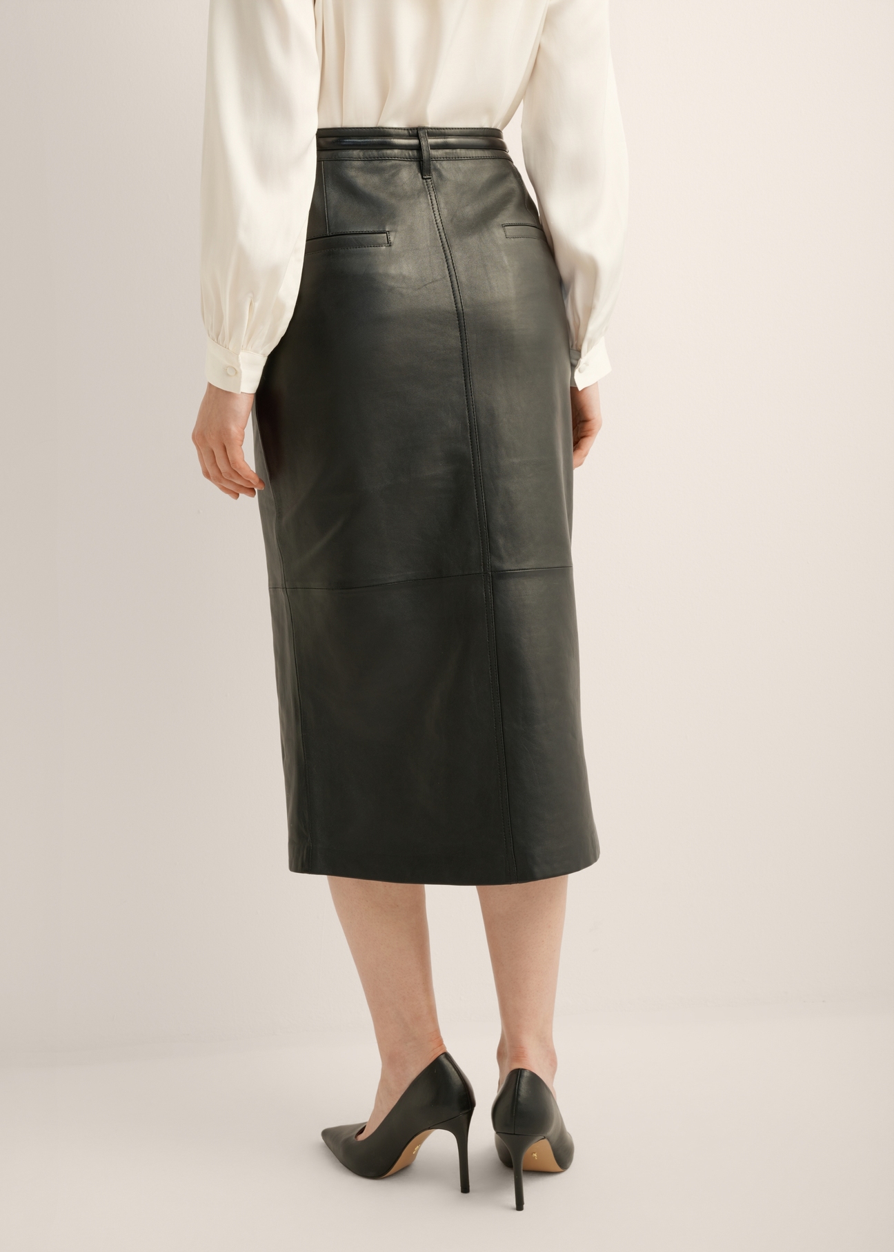 Black leather midi skirt SPCDS-0071-5344(Z25). Rear view of the product on the model. Half of the figure is visible.