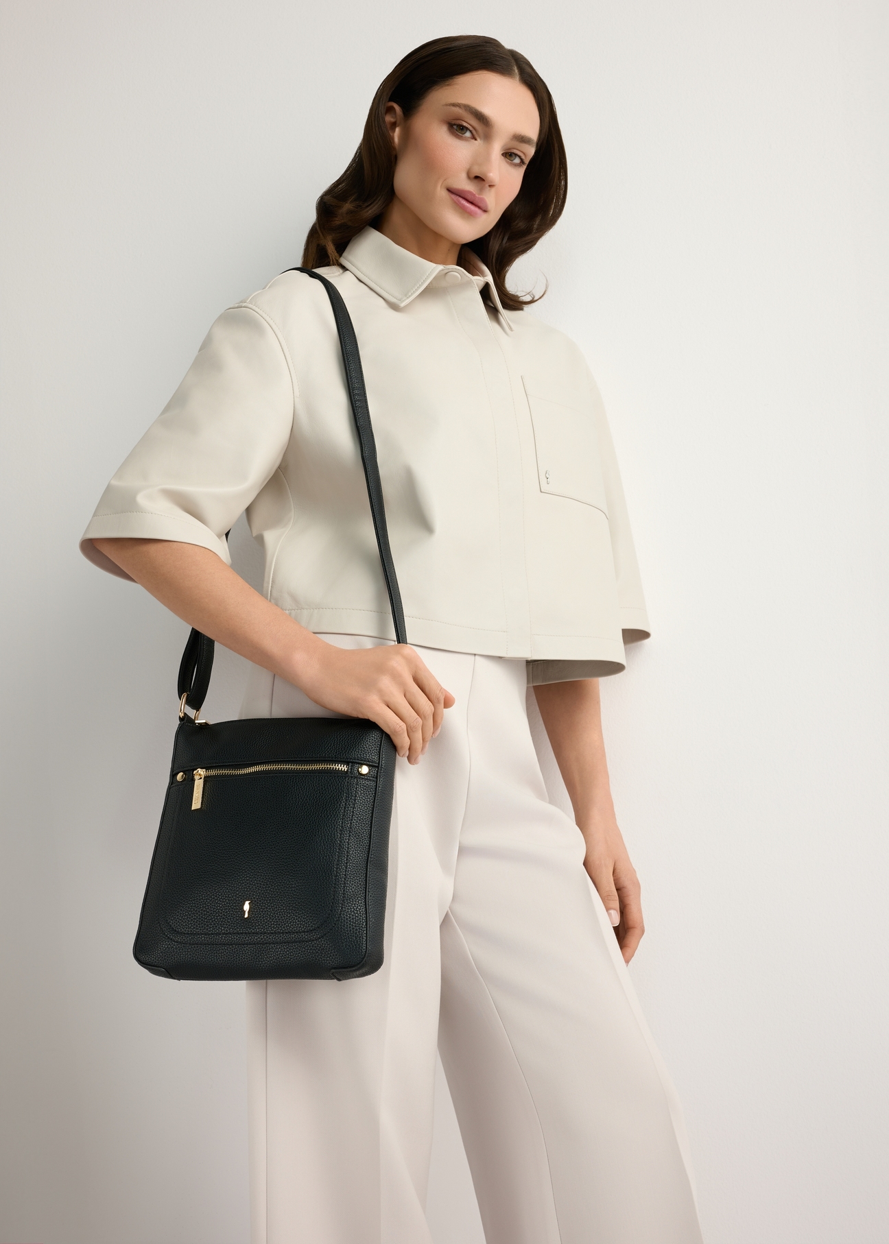 Women's black imitation leather messenger bag TOREC-1177-99(W26), front view of the product on a model, half of the silhouette visible.