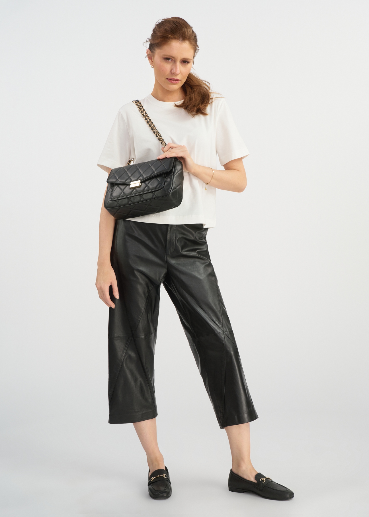 Black quilted imitation leather messenger bag TOREC-1022-99(W25) - diagonal view on model on white background. Full silhouette visible.