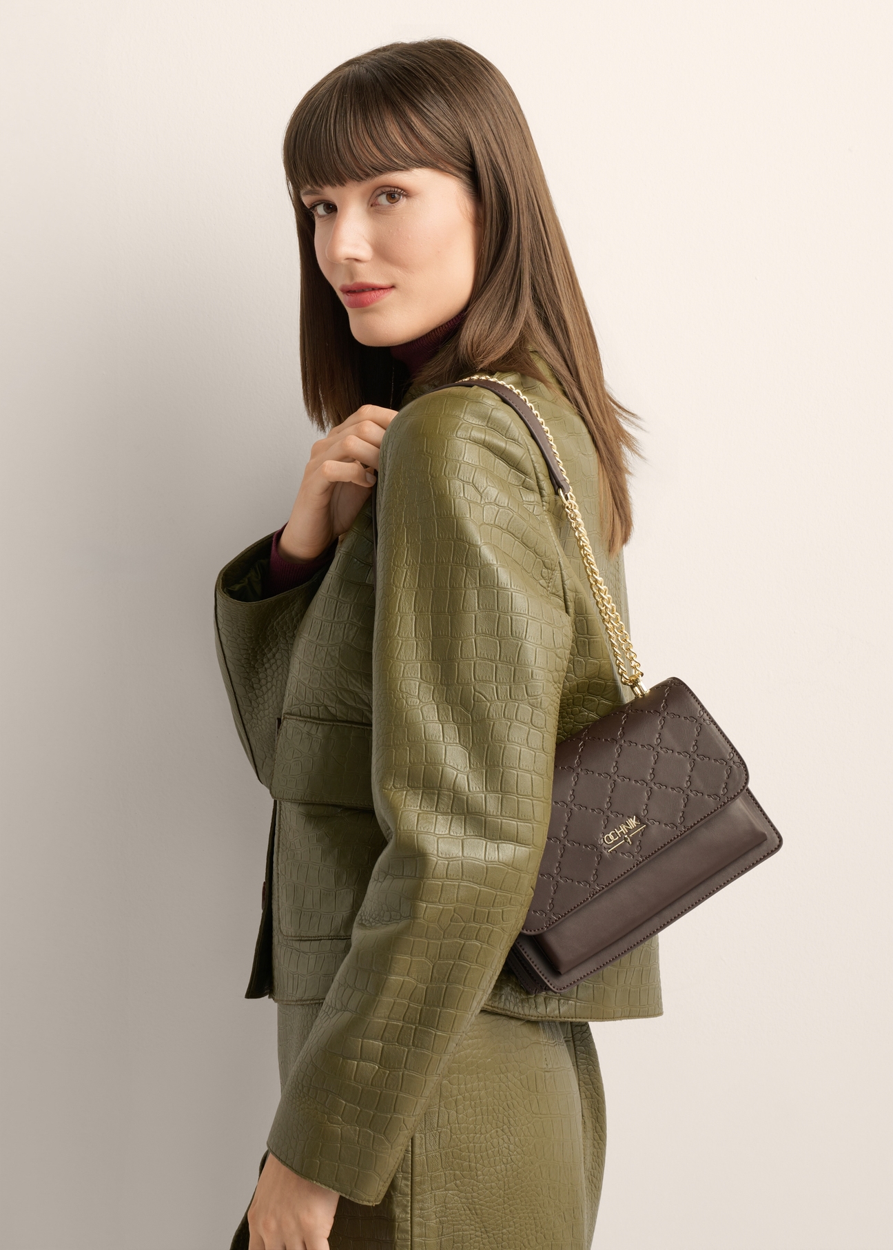 Brown women's monogrammed handbag TOREC-1155-1I(Z26), product view on model's shoulder. Half of silhouette visible.