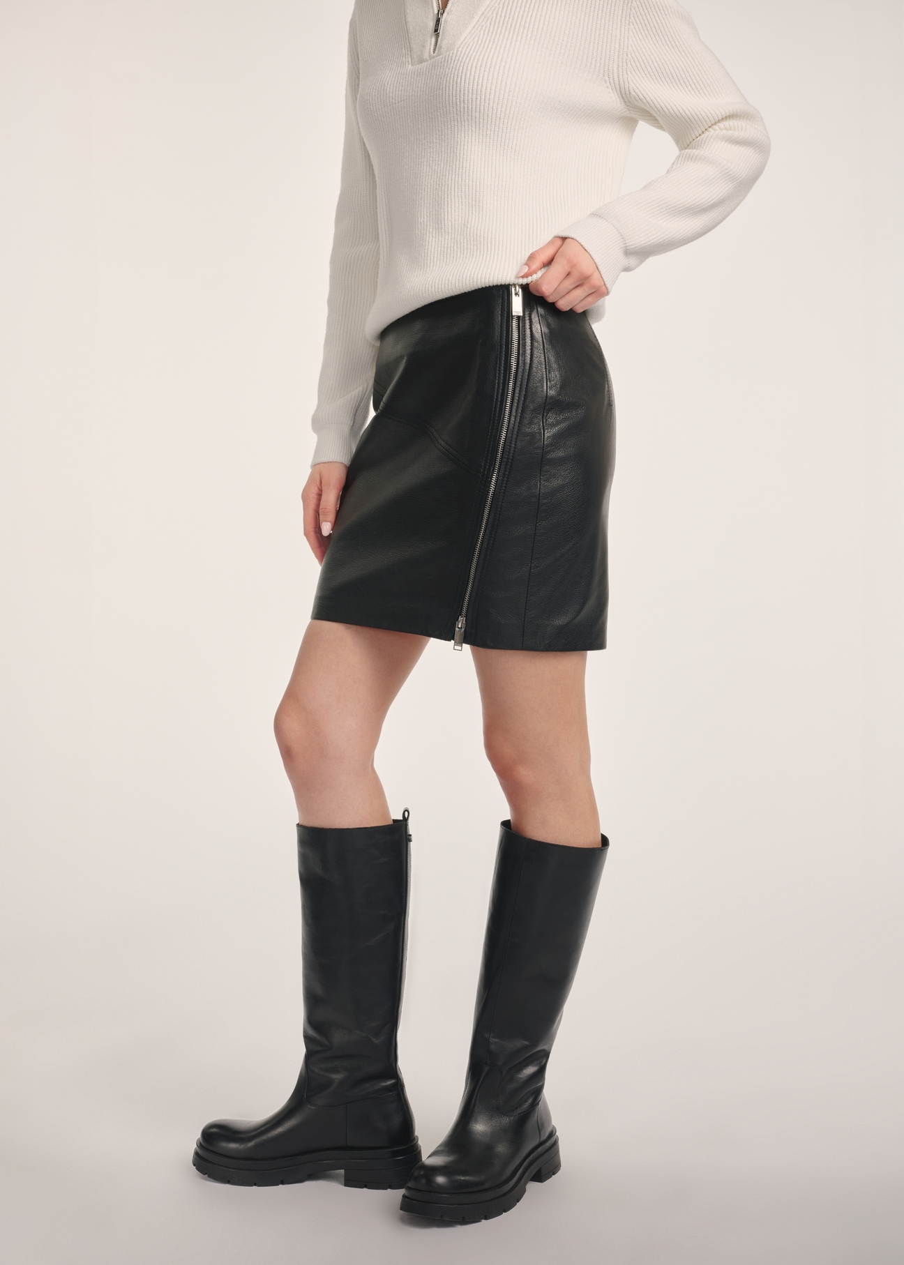 Black leather mini skirt SPCDS-0079-3206(Z25) - side view of the product on a model on a white background. Half of the silhouette visible.