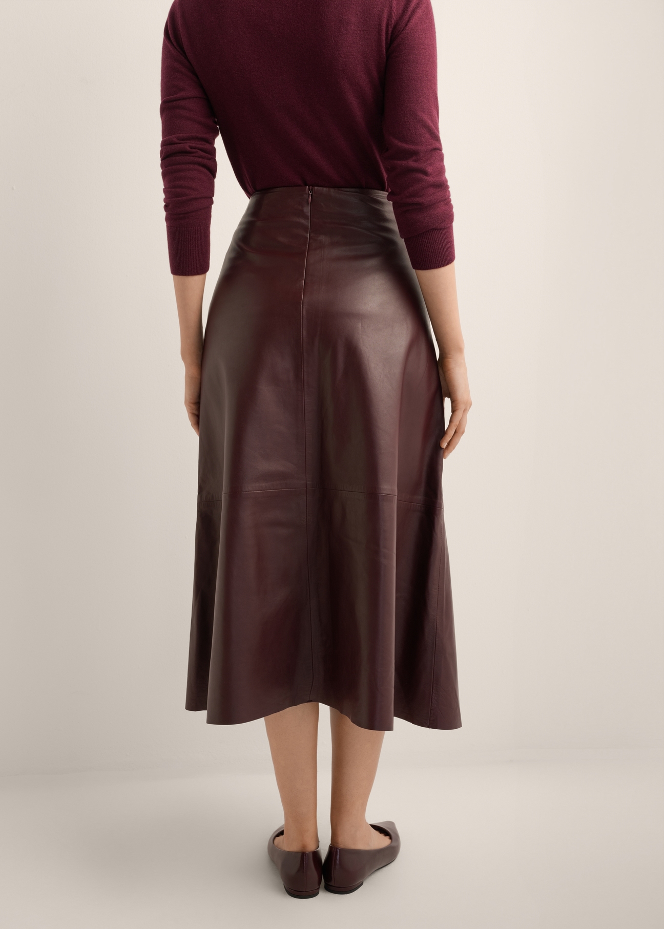 Burgundy leather midi skirt SPCDS-0077-4D(Z26), back view of the product on the model. Half of the silhouette visible.