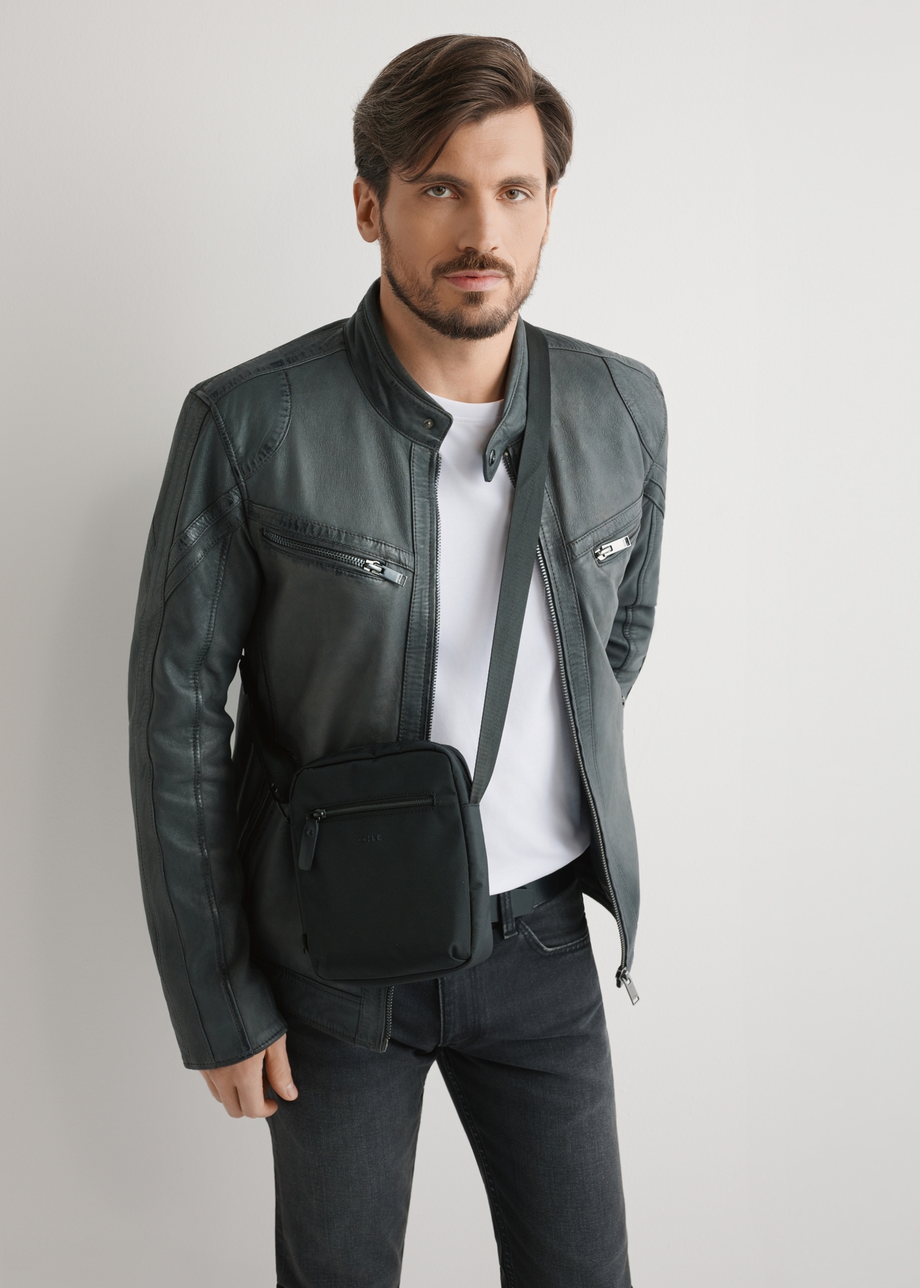 Men's black shoulder bag TORMN-0391-99(W26) - front view of the product, on a model, against a light background. Knee-length silhouette visible.