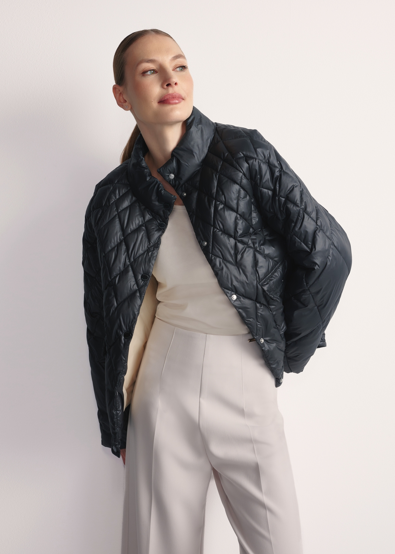 Black women's quilted jacket KURDT-0597-98(Z25), front view of the product on the model, half of the silhouette visible.-02