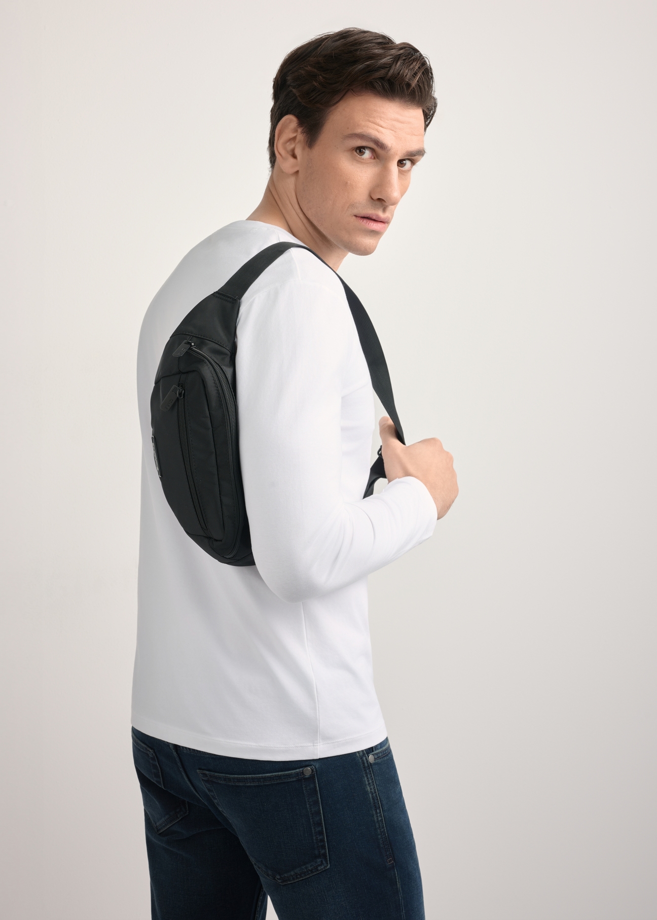 Men's black TORMN-0365-99(Z25) waist bag - diagonal view of the product, on a model, against a light background. Half of the silhouette visible.