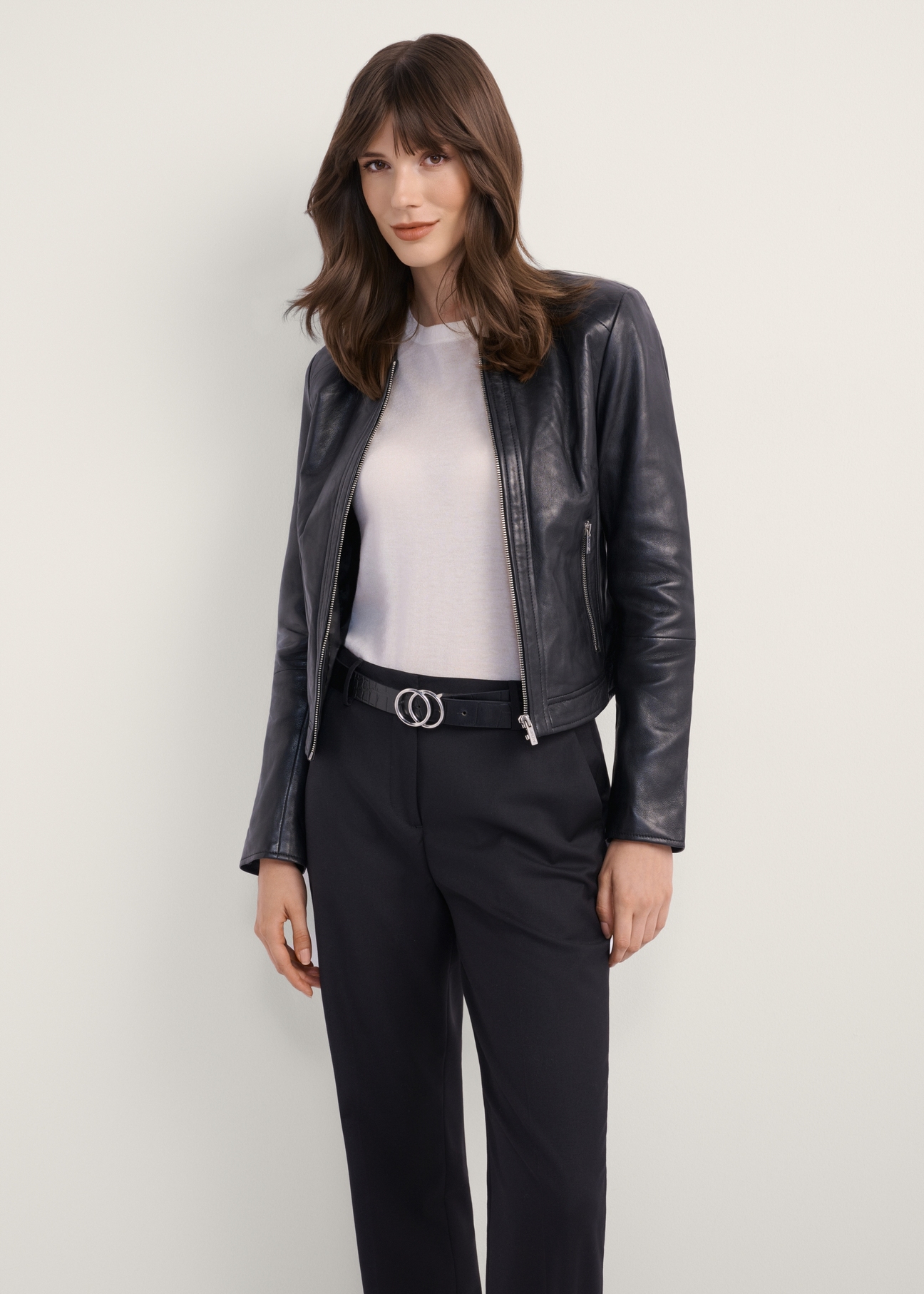 Women's black short leather jacket KURDS-0294-1340(KS), front view of the product on the model. Half of the silhouette visible.
