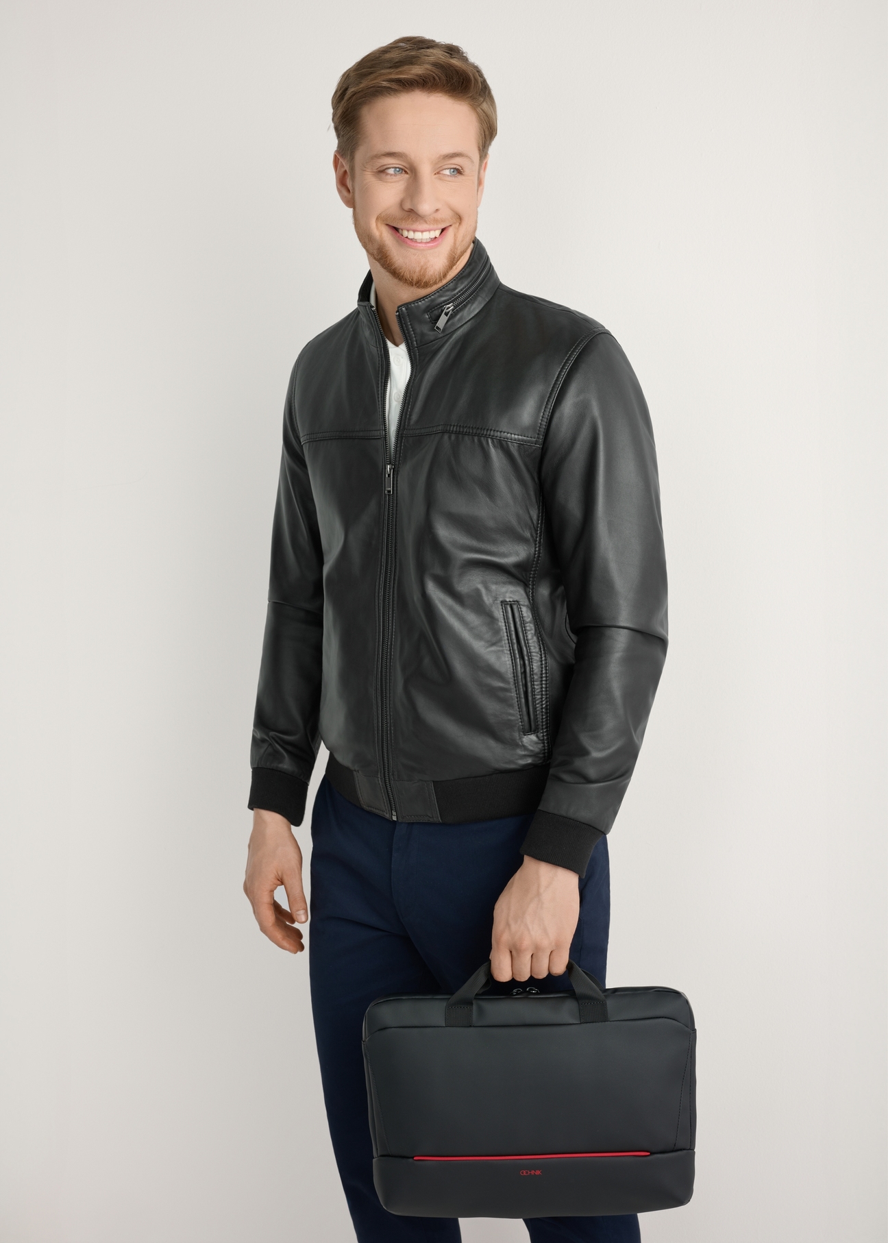 Black TORMN-0398-9J(W26) laptop bag - front view of the product, held by the model, against a light background. Knee-length silhouette visible.