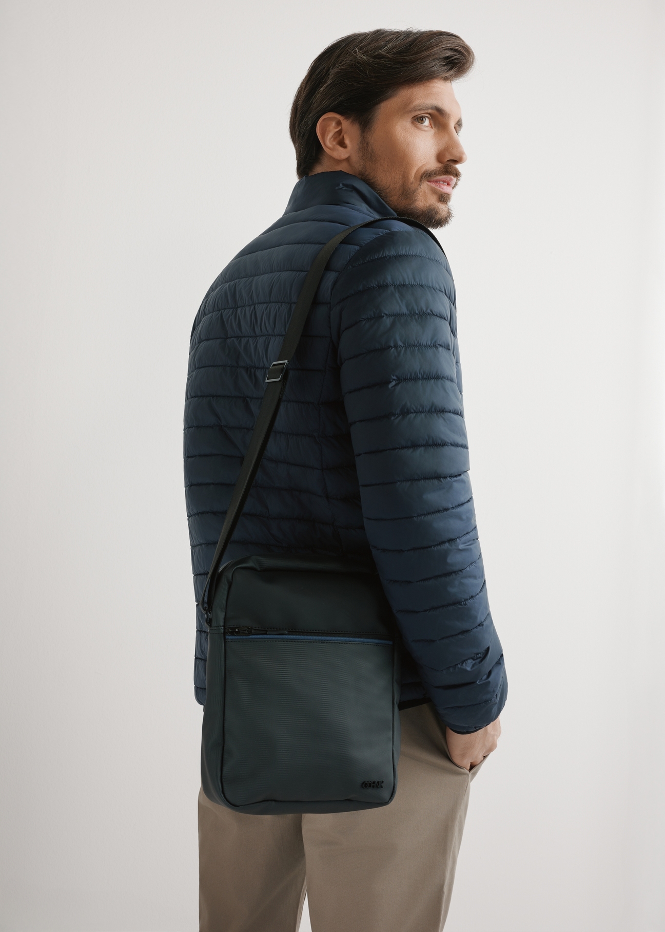 Men's black crossbody bag TORMN-0395-9J(W26) - front product view, on model, against a light background. Half-length silhouette visible.