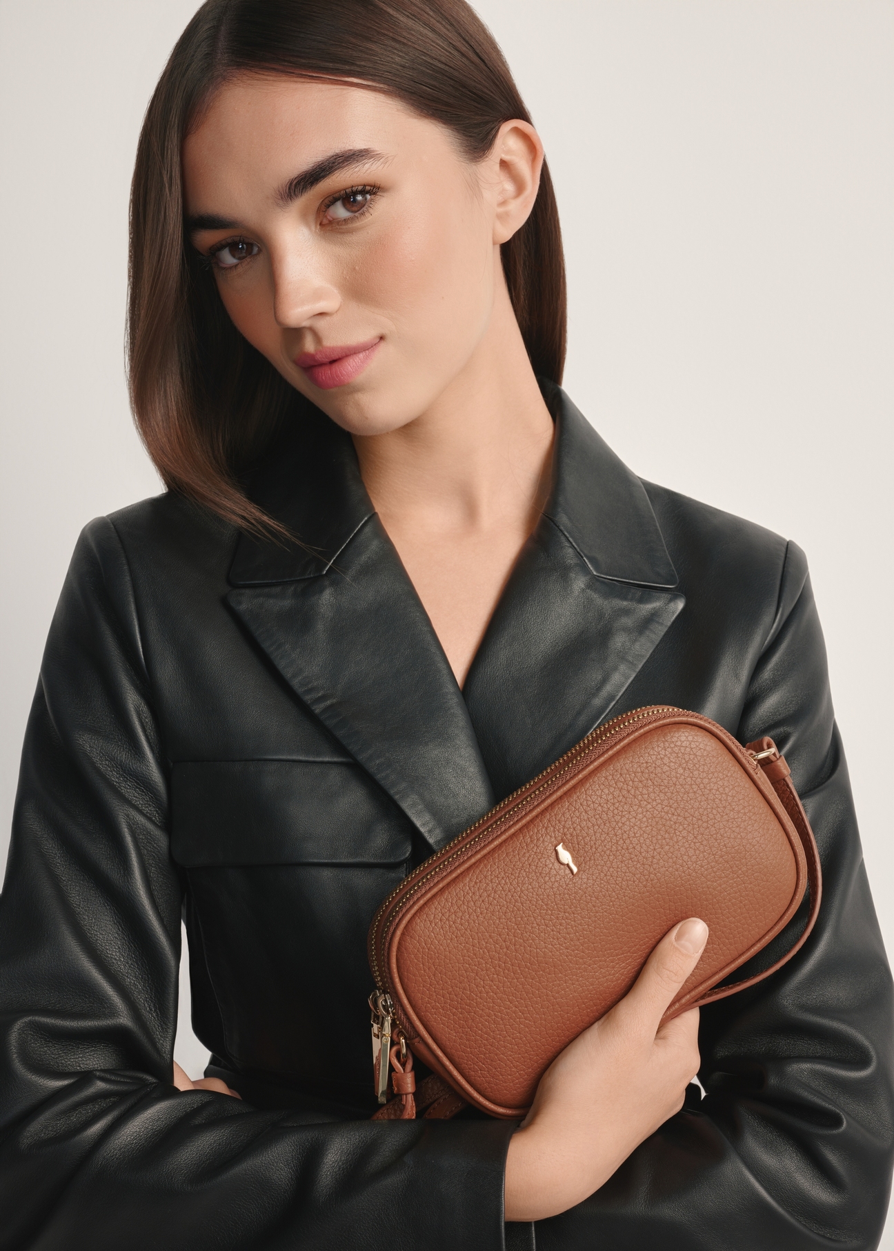 Small leather women's handbag in camel color TORES-0466E-1D(W26), product view from the front on the model, half of the silhouette visible.