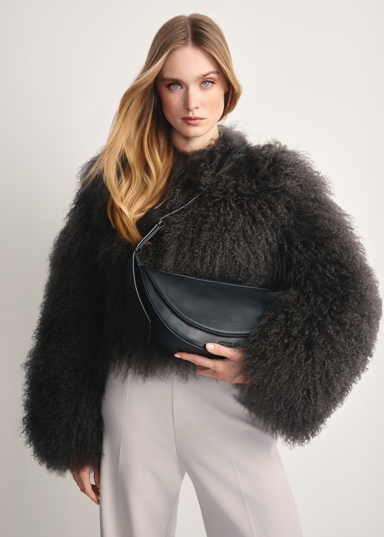 Black leather semi-circular women's handbag TORES-1178-99(Z25, front view of the product on the model, half of the silhouette visible.
