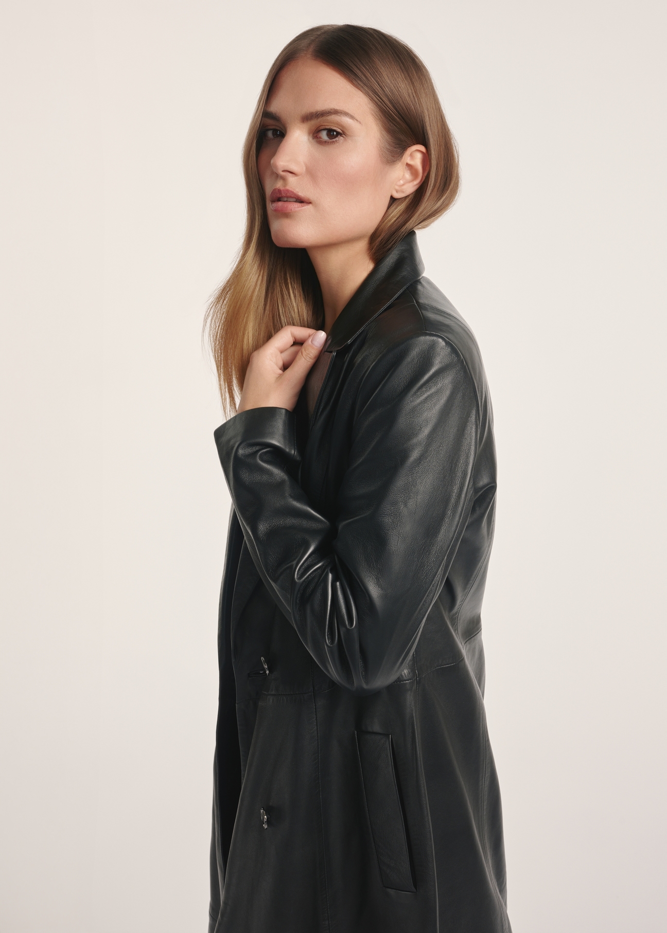 Black women's leather coat KURDS-0546-5344(Z25), product visible from the side on the model, half of the silhouette visible.