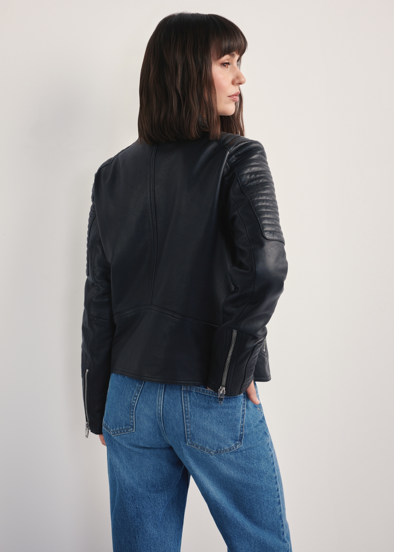 Women's black leather jacket KURDS-0560-3943(Z25), back view of the product on the model. Half of the silhouette visible.