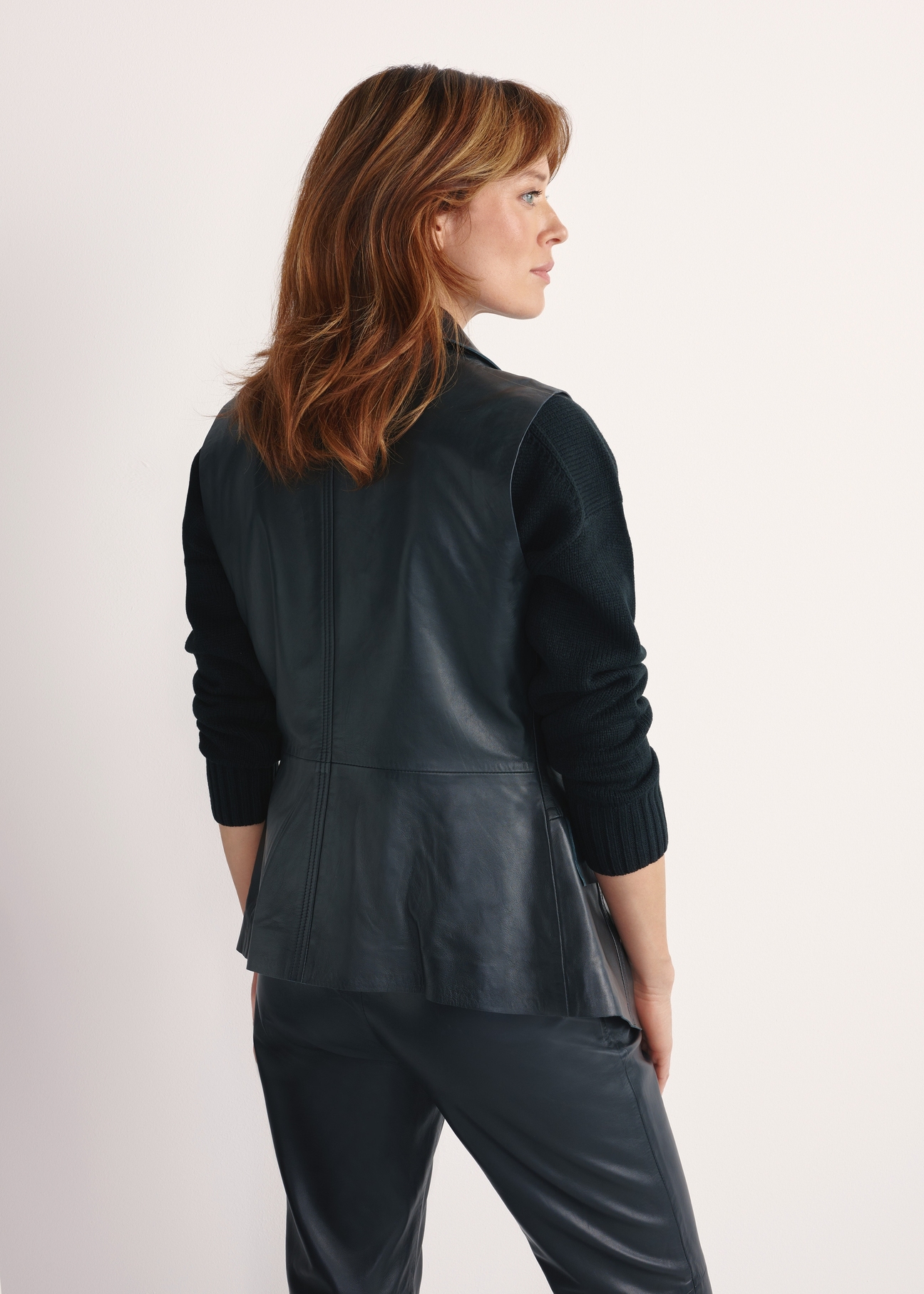 Women's black leather vest KAMDS-0010-5344(W25), product view from the back on the model, half of the silhouette visible.