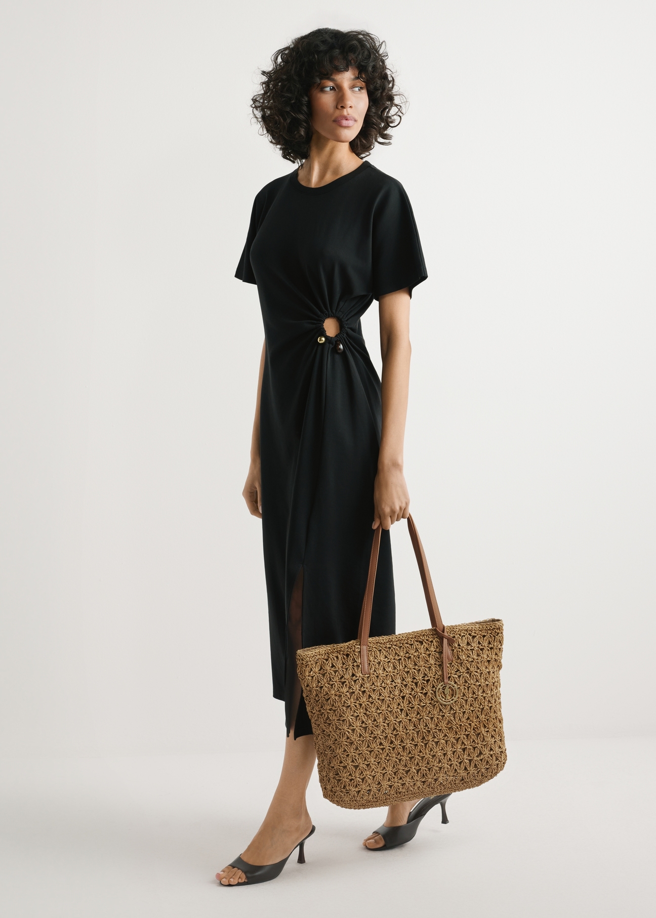 Straw shopper bag TOREC-1218-1E(W26) - slightly diagonal view of the product, held by the model, against a light background. The entire silhouette is visible.