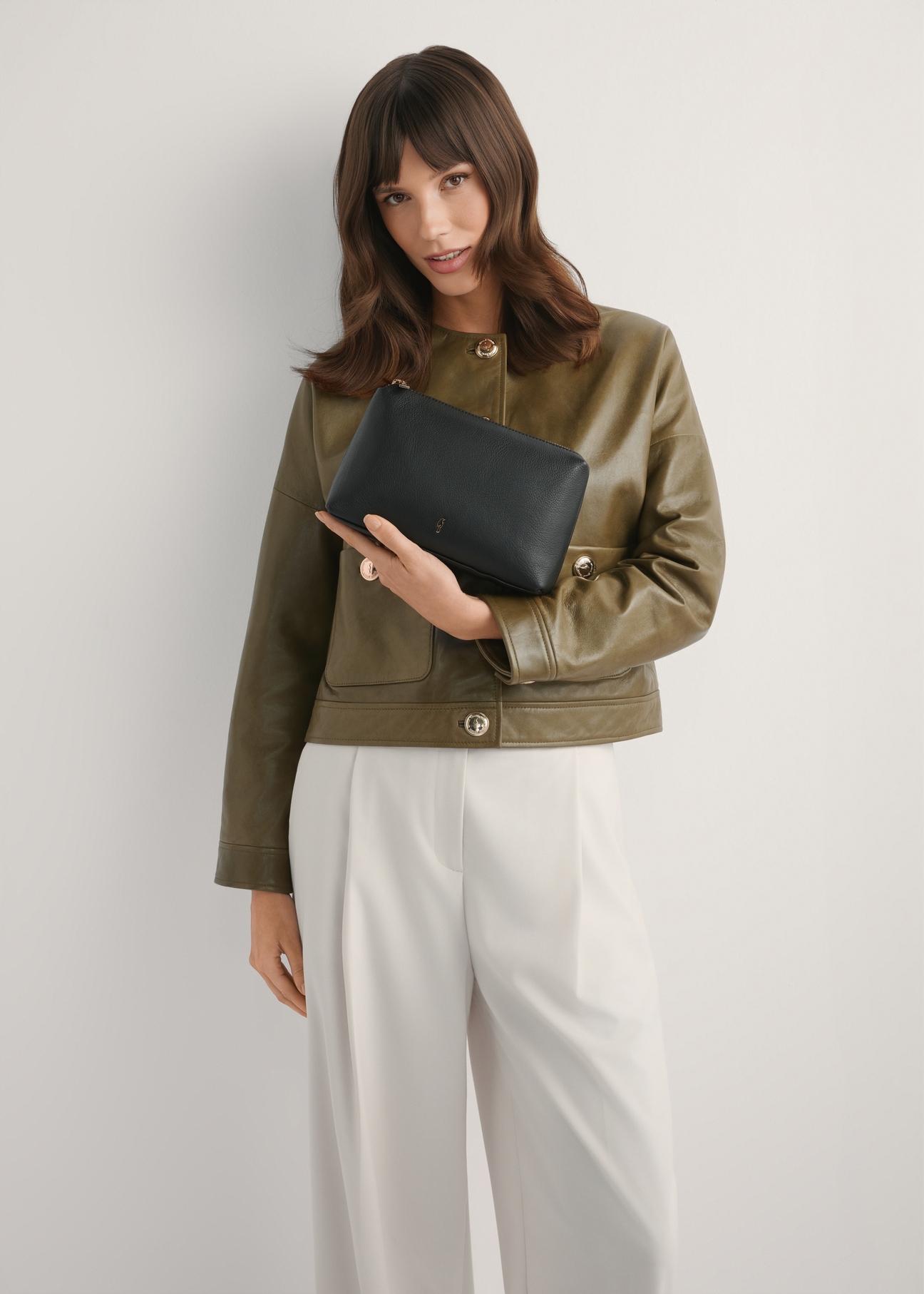 Black leather women's cosmetic bag TORES-1229-99(W26), front view of the product on a model, half of the silhouette visible.