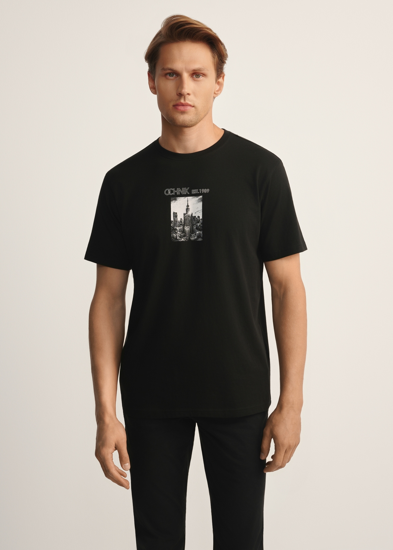 Black men's T-shirt with print TSHMT-0132-99(Z25), front view of the product on the model, half of the silhouette visible.
