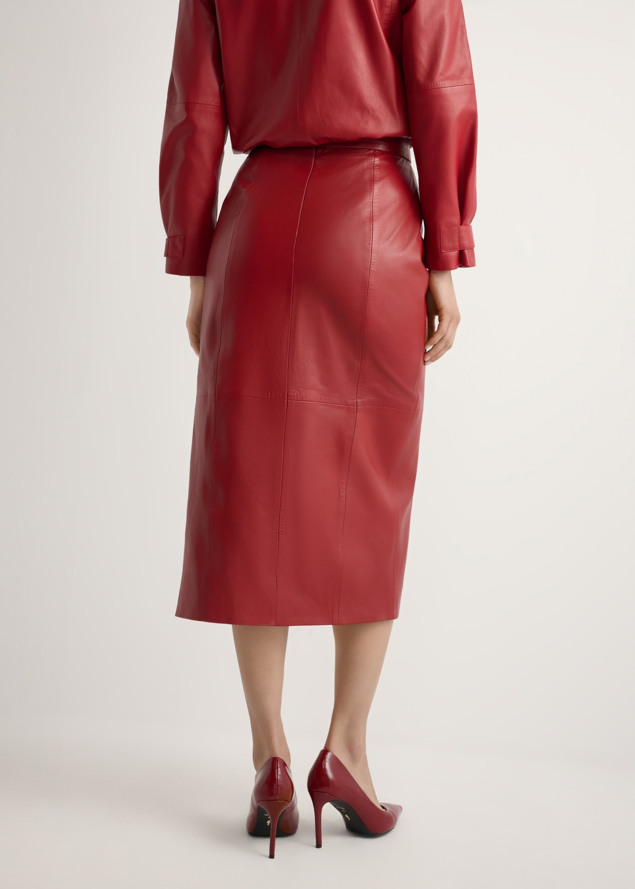 Women's long red leather skirt with slit SPCDS-0075-4B(W26), product view from the back on the model. Half of the silhouette visible.