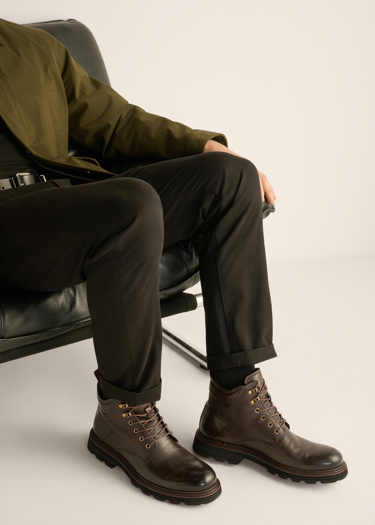 Men's brown leather ankle boots BUTYM-0569-1I(Z26) - side view of the product, on a model, against a light background. Half of the silhouette visible.