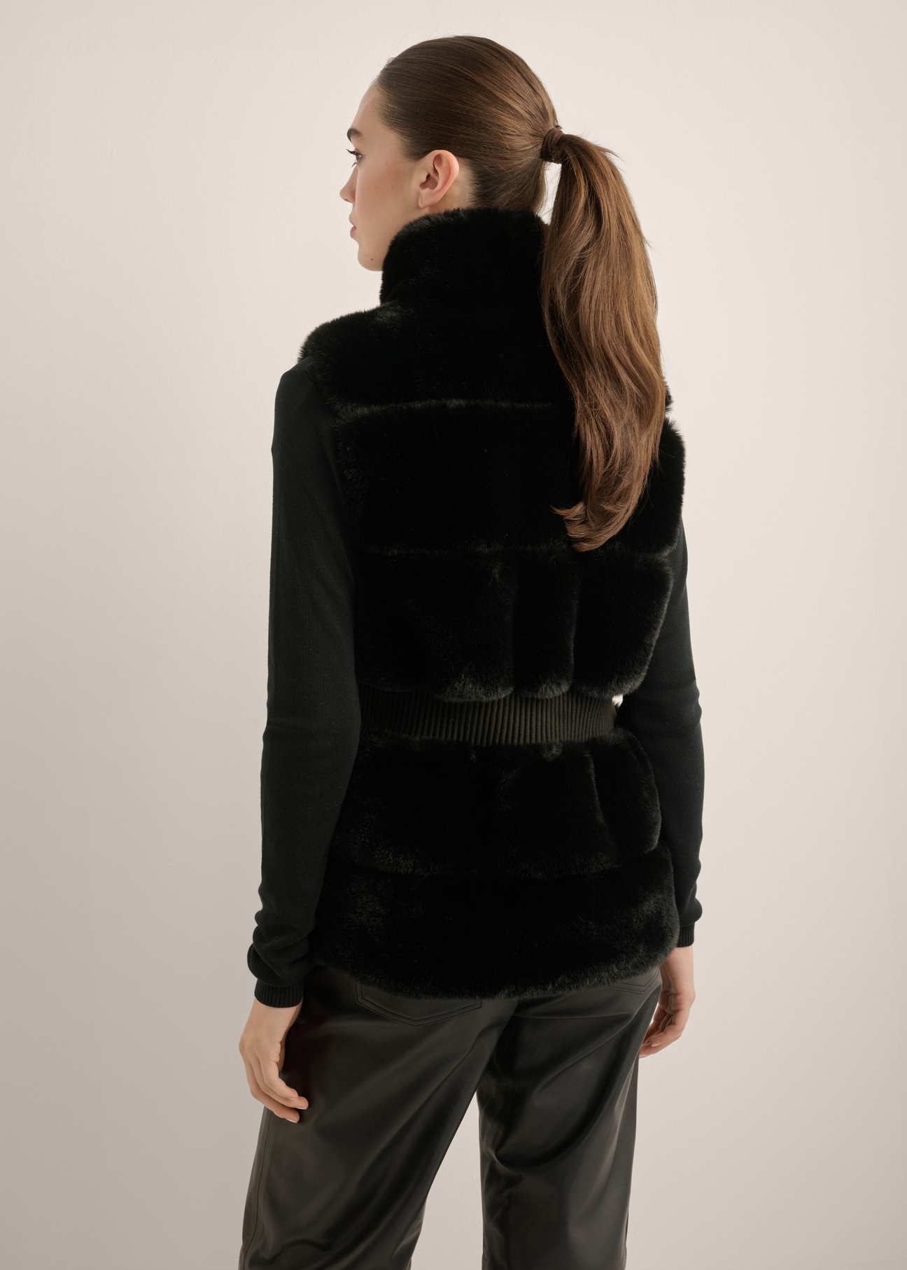 Women's black fur vest KAMDP-0006-99(Z25), product view from the back on the model. Half of the silhouette visible.