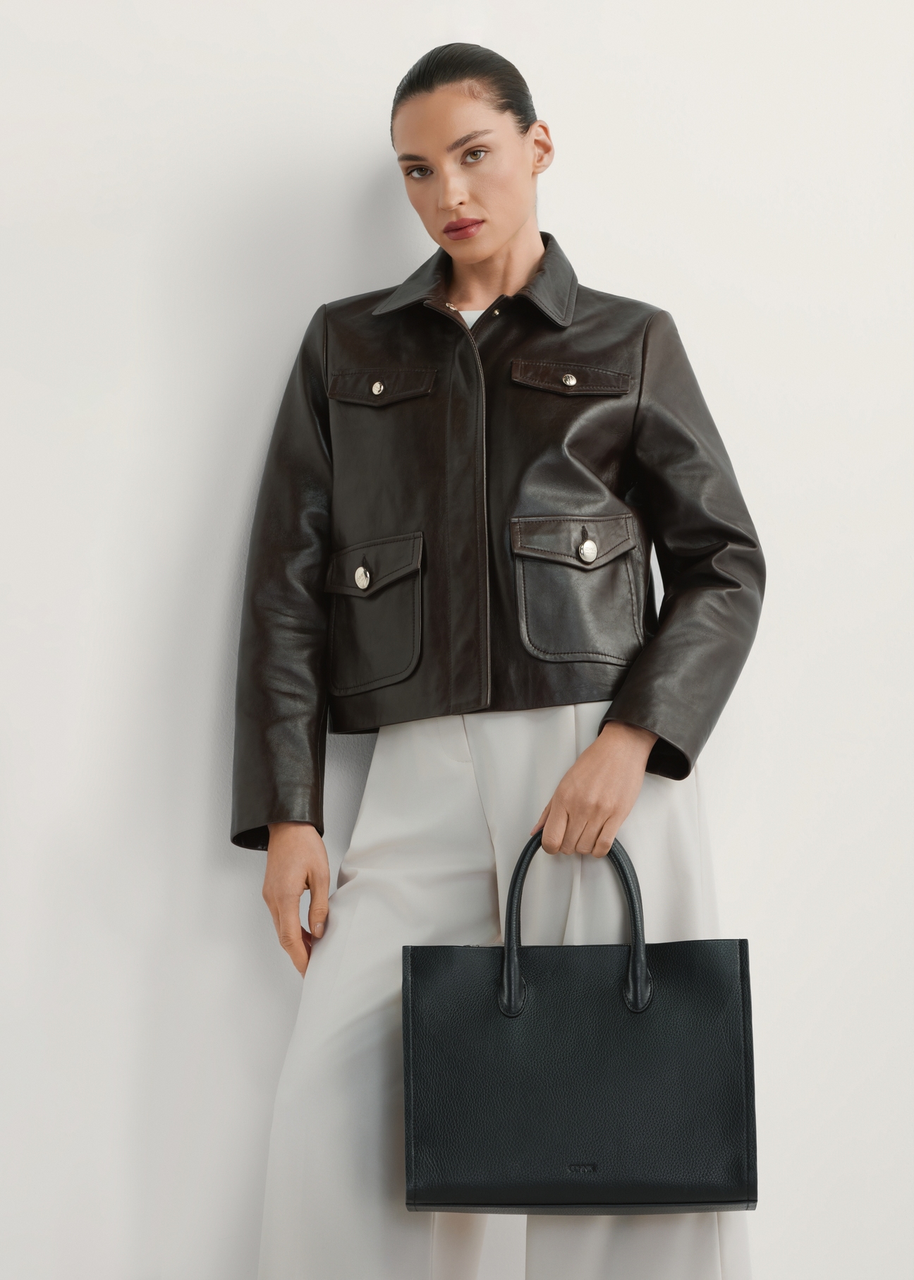 Women's black leather handbag TORES-1206-9I(W26), product view in model's hand. Half of silhouette visible.