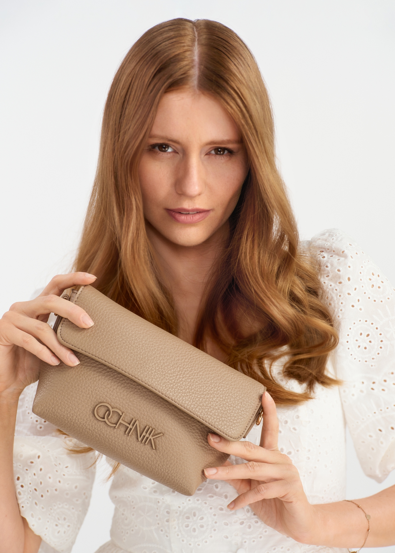 Light beige small women's handbag with logo TOREC-0916A-81(W25) - view of a model holding the product, on a white background.