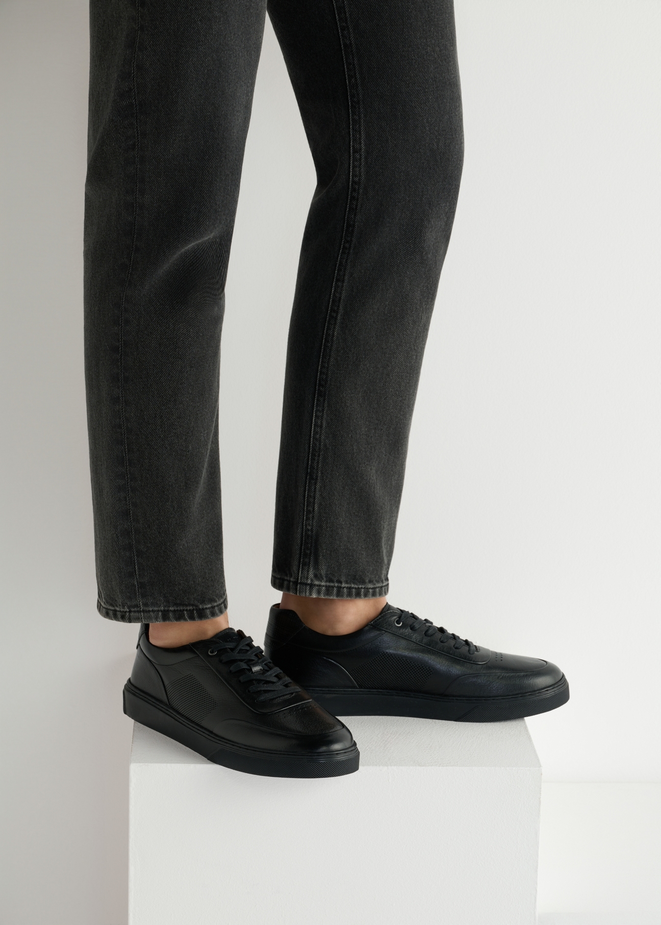 Black leather men's sports shoes BUTYM-0484-99(W25), side view of the product on the model, half of the silhouette visible.