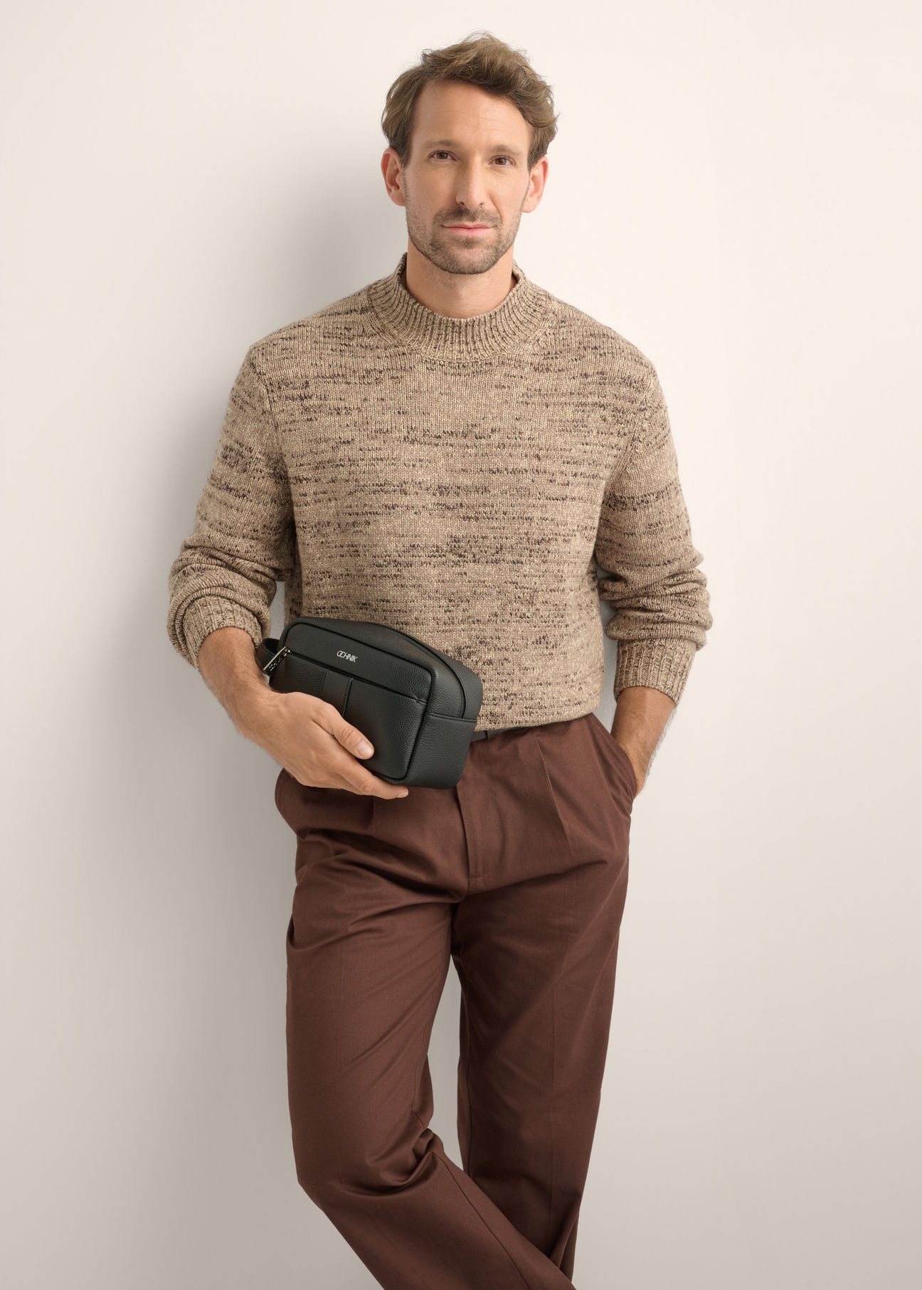 Black leather men's cosmetic bag TORMS-0537-9I(Z26), diagonal view of the product on the model. Half of the silhouette visible.