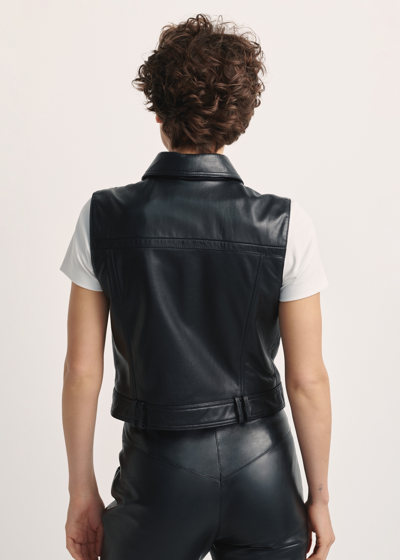 Women's leather vest KAMDS-0011-5491(Z25), product view from the back on the model. Half of the silhouette visible.