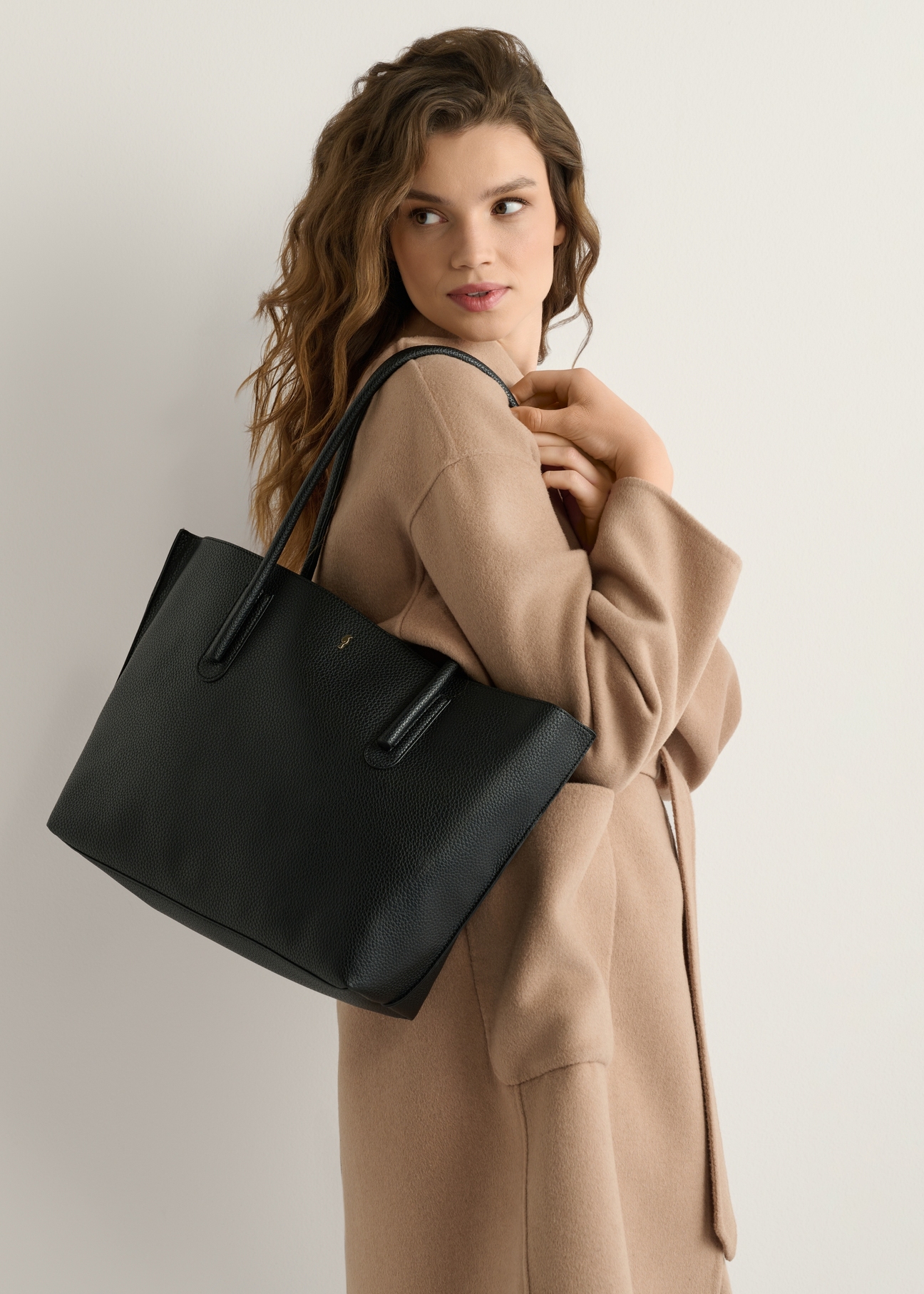 Black women's shopper bag TOREC-0938-99(W24), front view of the product on a model, half of the silhouette visible.