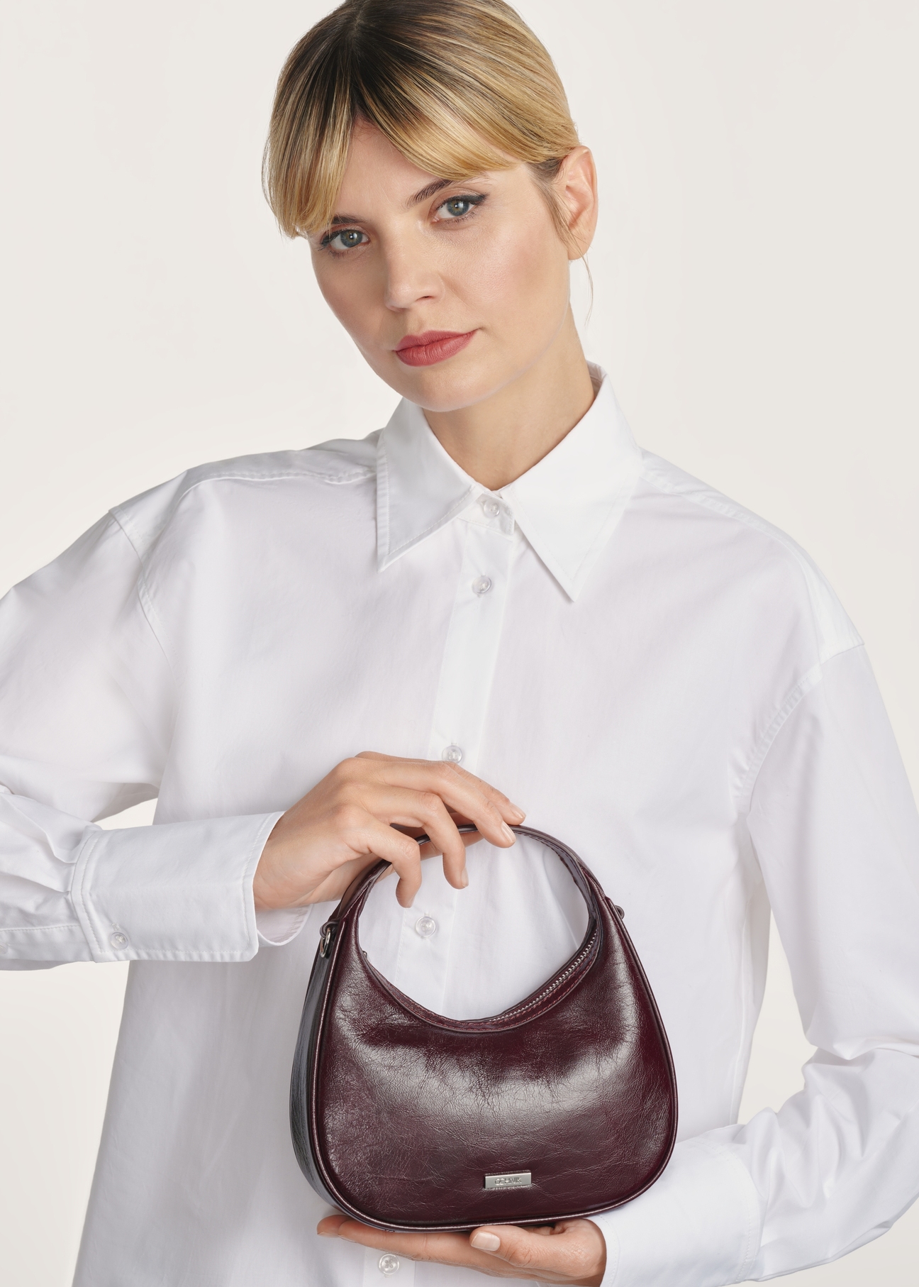 Small burgundy leather hobo bag TORES-1174-49(Z25), front product view on model on white background. Half of the silhouette visible.