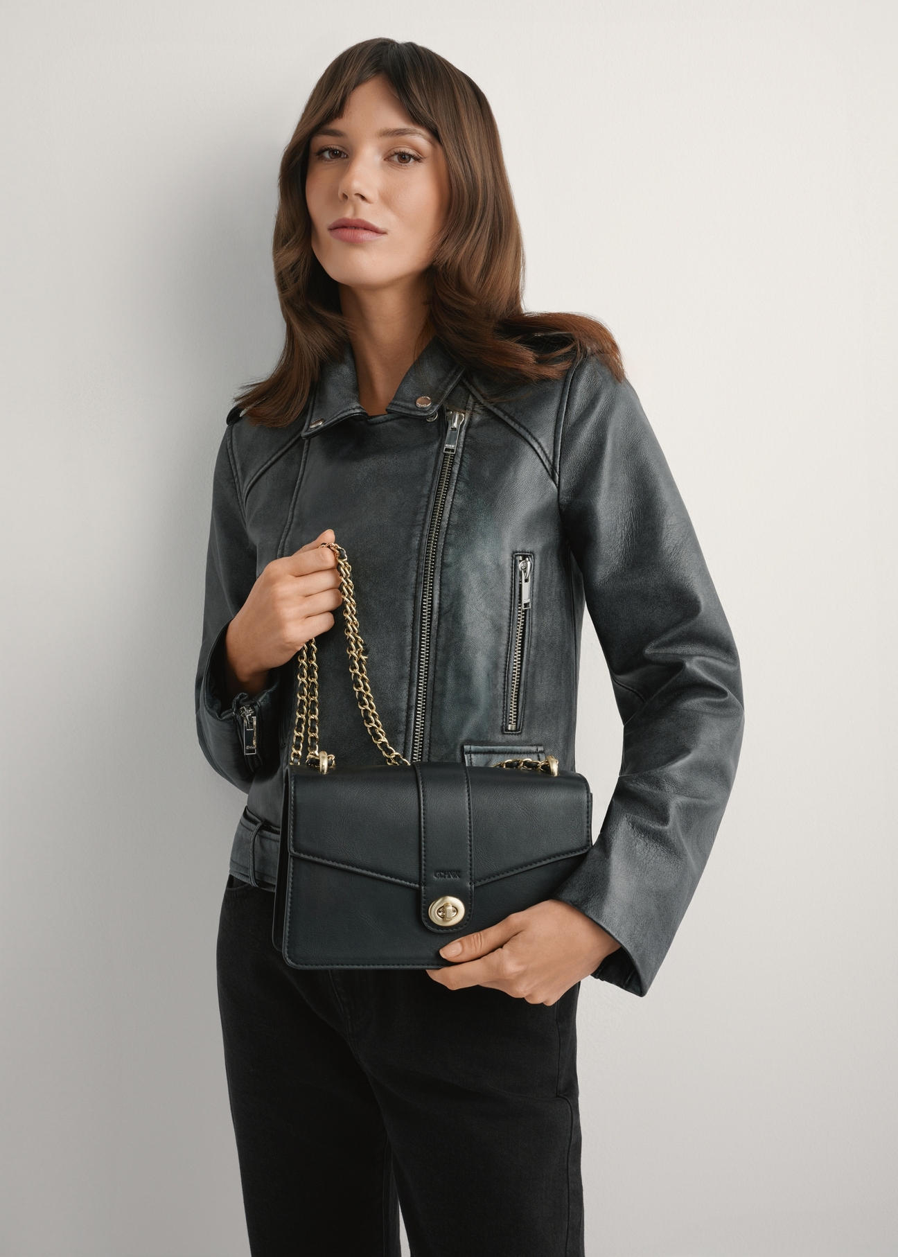 Black women's messenger bag TOREC-1137-99(W26), product view in model's hands. Half of silhouette visible.