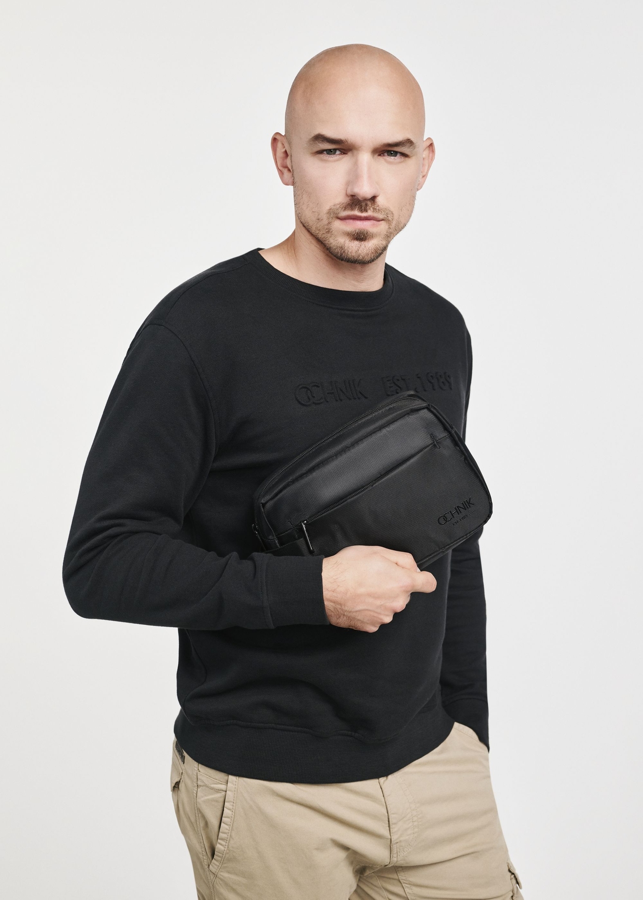Black men's cosmetics bag TORMS-0267C-99(Z25), close-up of the product in the model's hand. Half of the silhouette visible.