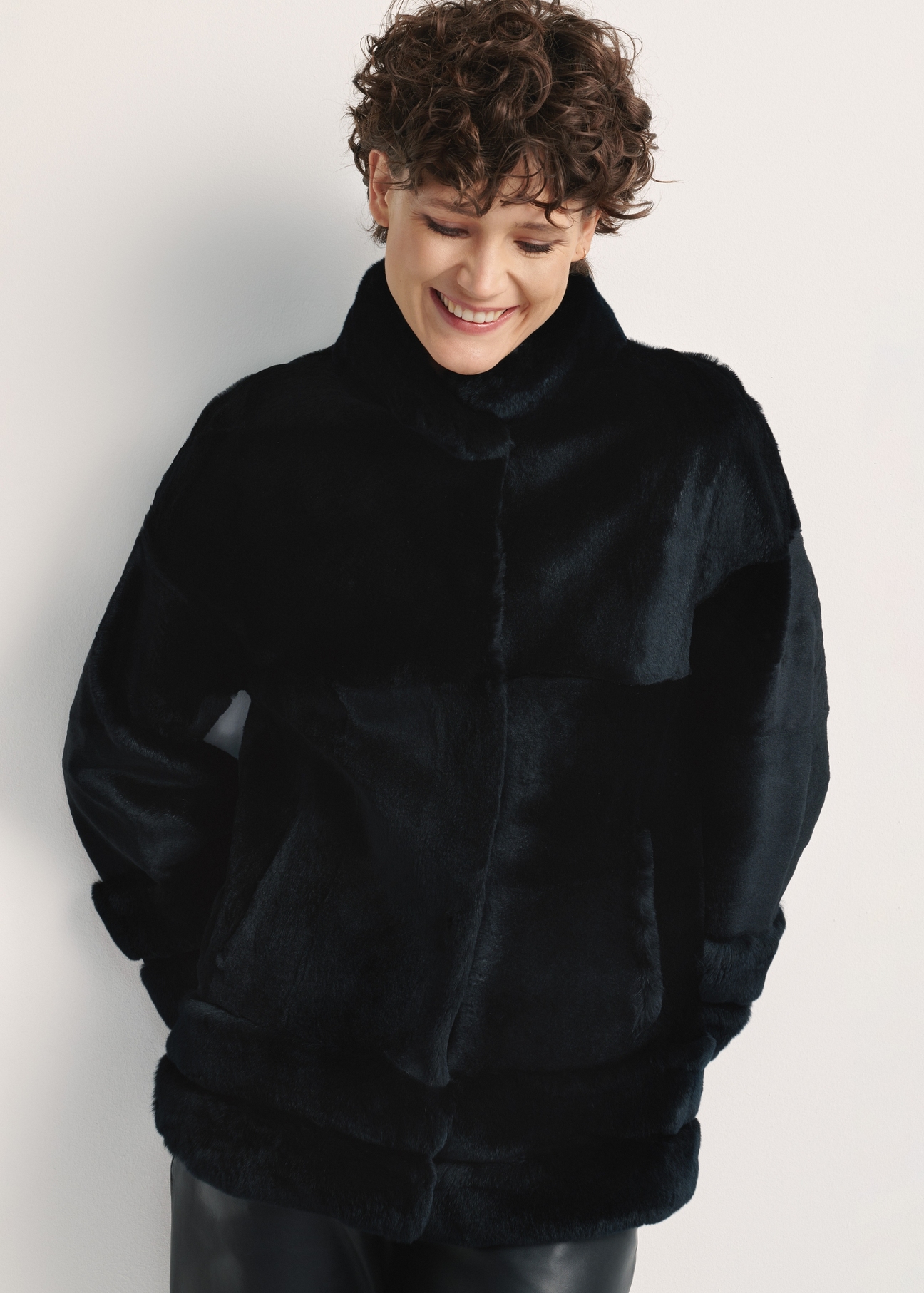 Black women's fur coat with a stand-up collar, natural FUTDF-0077-0984(Z24), front view of the product on a model, half of the silhouette visible.