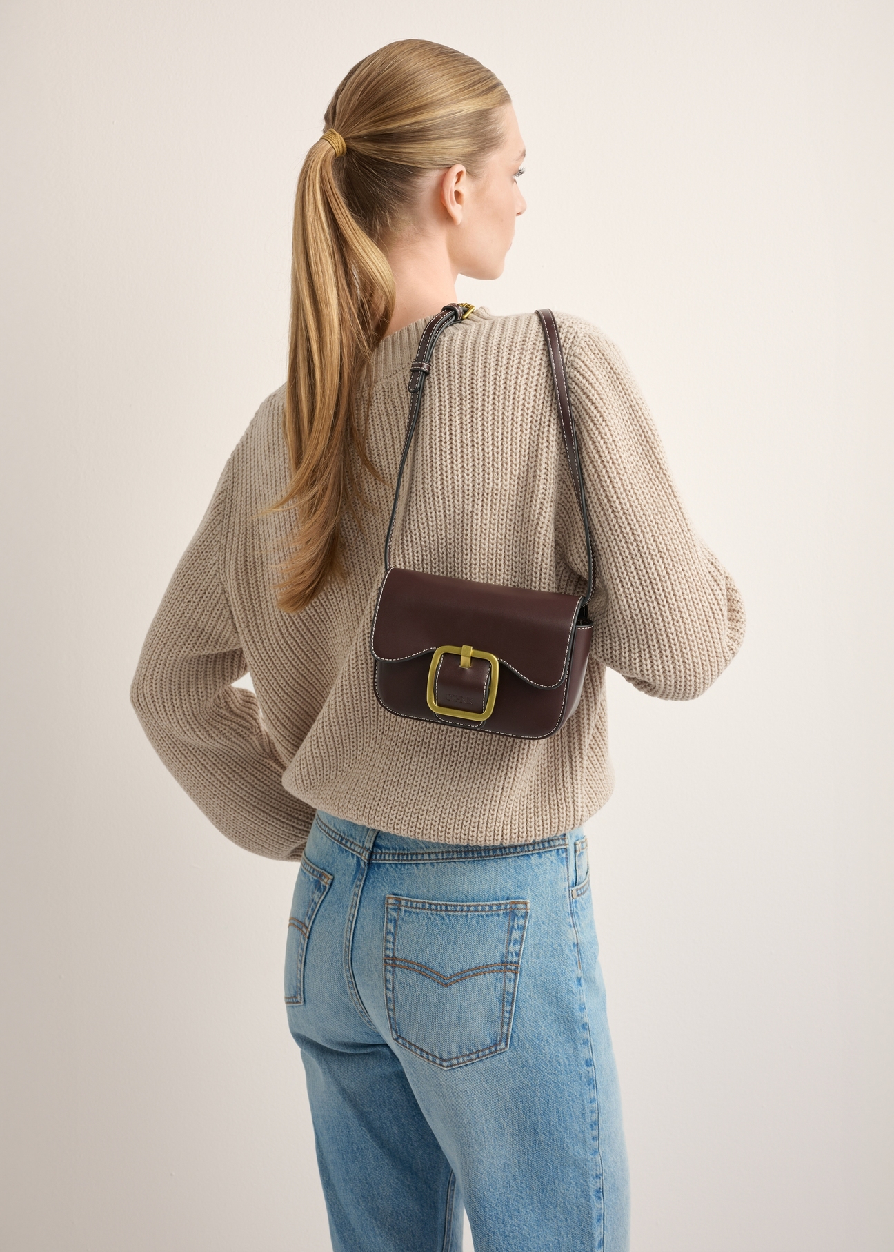 Small brown women's handbag with a buckle TOREC-1383-1H(Z26), front view of the product on a model. Half of the silhouette visible.