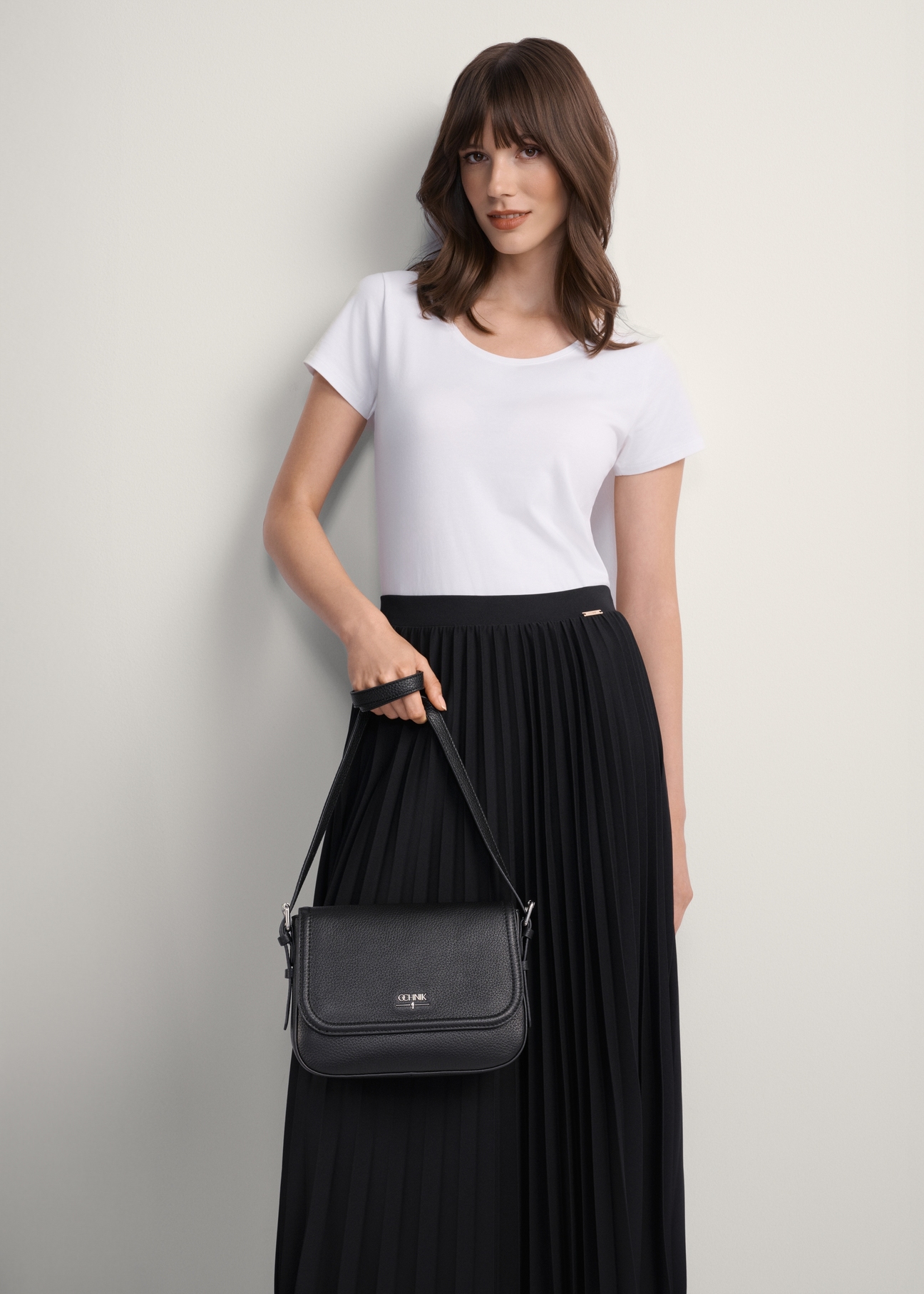 Women's black leather messenger bag TORES-0985D-99(Z25), front view of the product on a model, half of the silhouette visible.