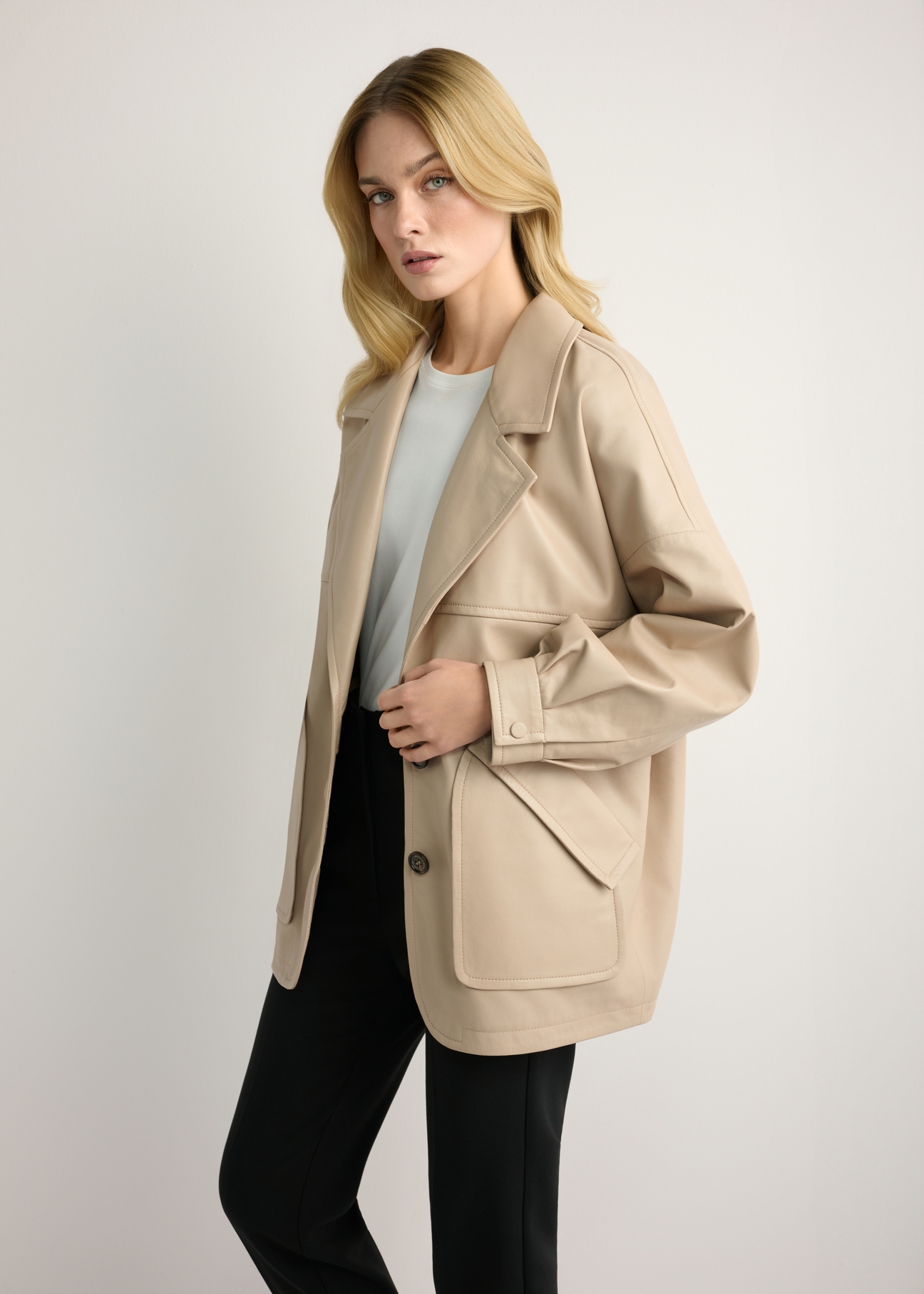 Beige oversize women's leather jacket KURDS-0577-1B(W26) - side view of the product, on a model, against a light background. Knee-length silhouette visible.