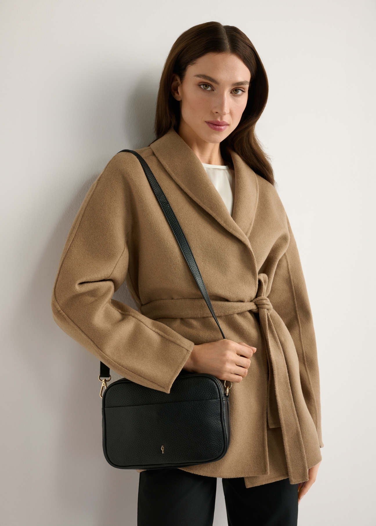 Small black leather women's handbag TORES-1284-9I(W26) - front view of the product, on a model, against a light background. Half-length silhouette visible.