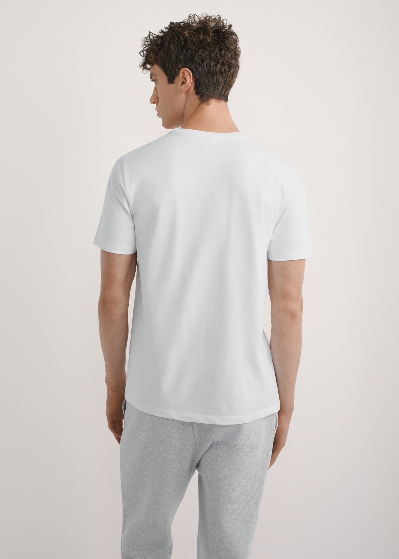 Men's white T-shirt TSHMT-0137-0A(W26) - back view of the product, on a model, against a light background. Knee-length silhouette visible.
